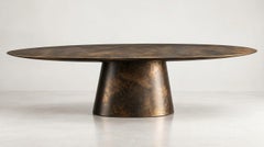 Tavolo da pranzo scultoreo in stile contemporaneo con piano ellittico e finitura in bronzo ossidato