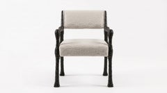Sillón de comedor esculpido a mano con estructura de madera cincelada teñida de oscuro y tejido bouclé