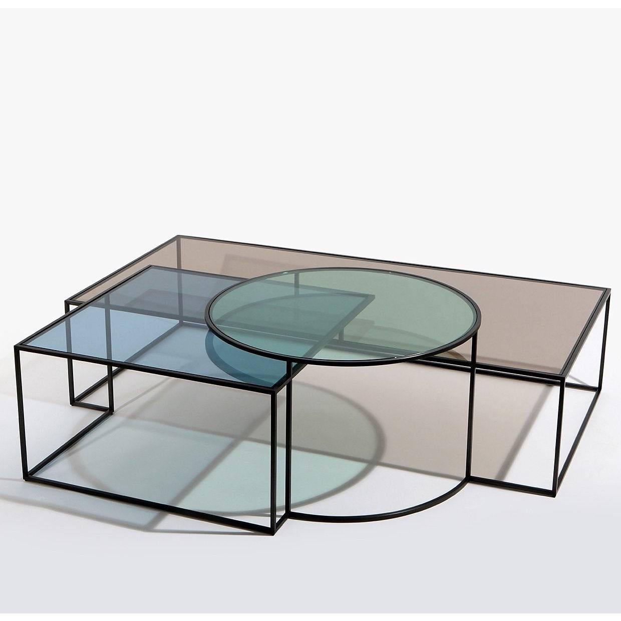 La table basse Geometrik de l'architecte Nada Debs est une composition de trois formes géométriques. Les ombres sont créées par la superposition des formes. Verre à cadre en acier noirci : Coloré en trois nuances douces de rouge, bleu et