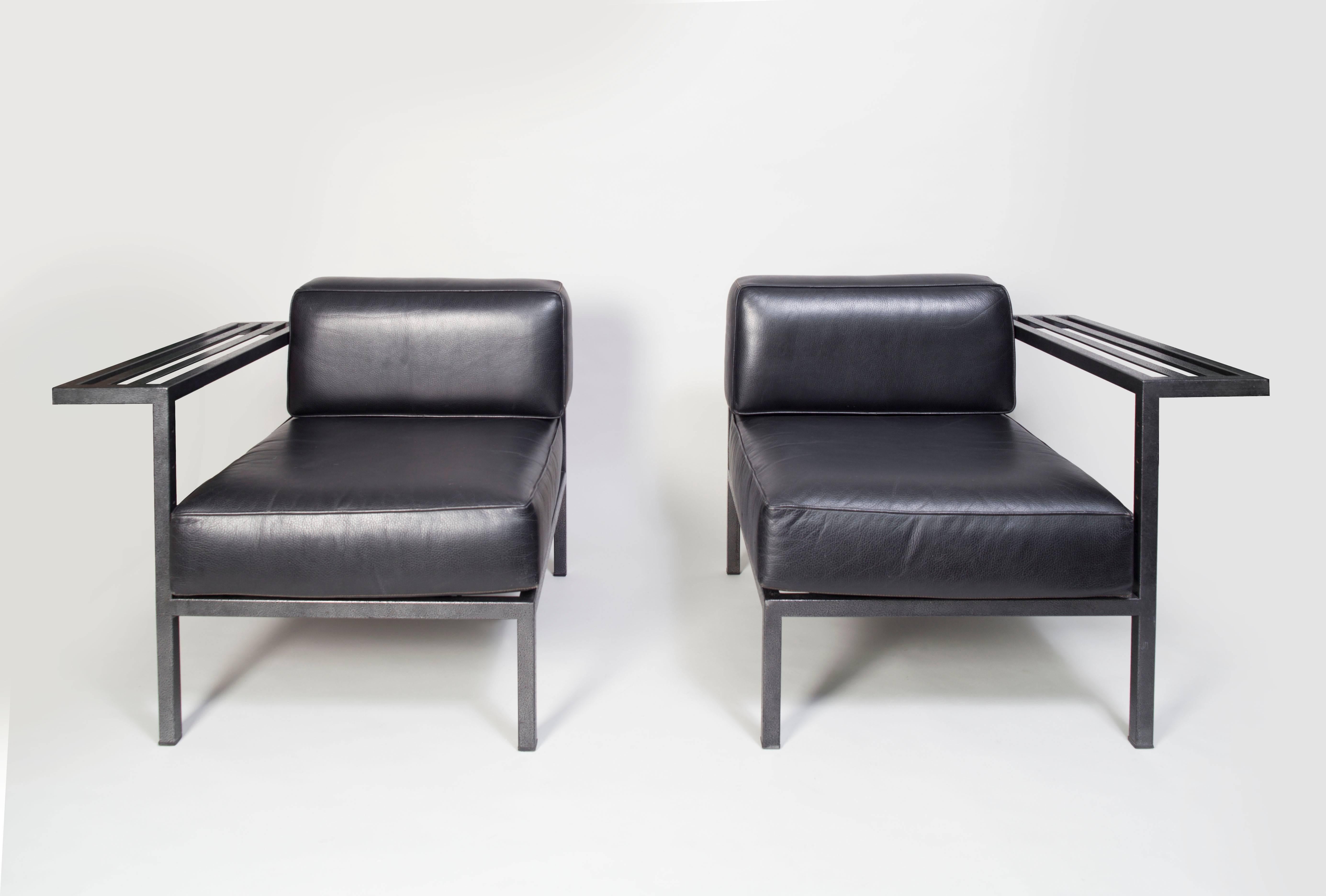 20th century pair of French black leather armchairs-sofa from the 1980s.
The structure has a lightly hammered surface. 
The two asymmetric armchairs, if joined together, create a loveseat.