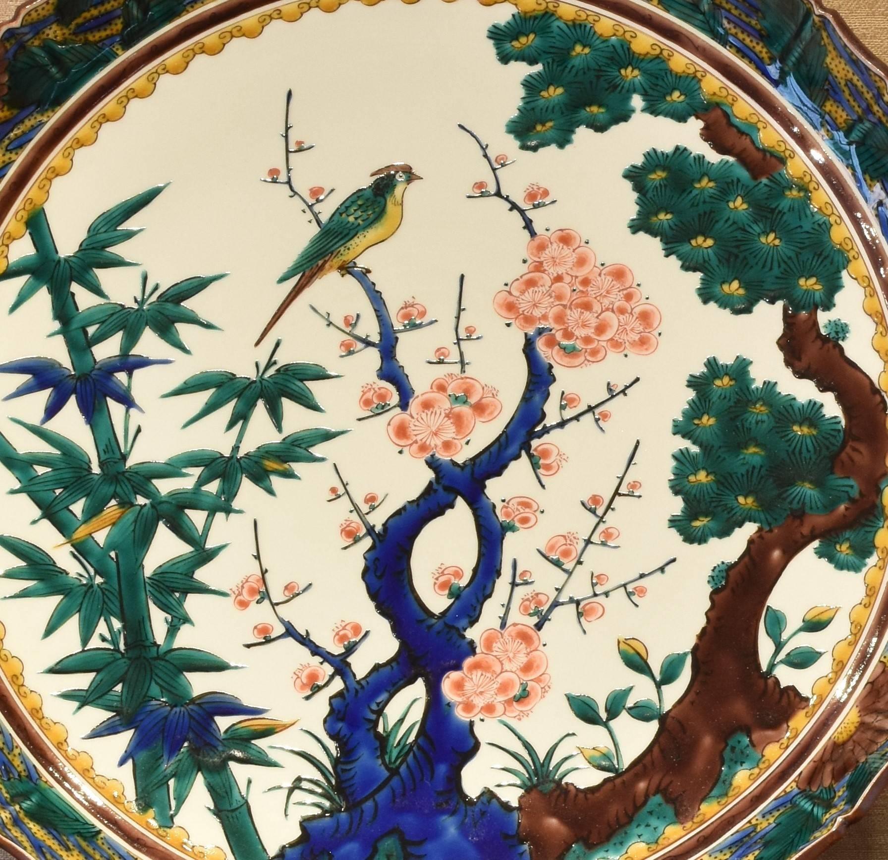 Exquisite Japanese contemporary decorative porcelain charger, hand painted in traditional Kutani colors of blue, red and green with the sho-chiku-bai, or Friends of the Winter motif, a signed work by the third generation master of a Kutani kiln with