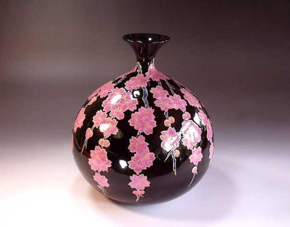 Exquisite dekorative Vase aus zeitgenössischem japanischem Porzellan, aufwändig vergoldet und handbemalt in leuchtendem Rosa und Blau auf einem eiförmigen Porzellankörper, vor einem dramatischen schwarzen Hintergrund. Ein signiertes Werk des
