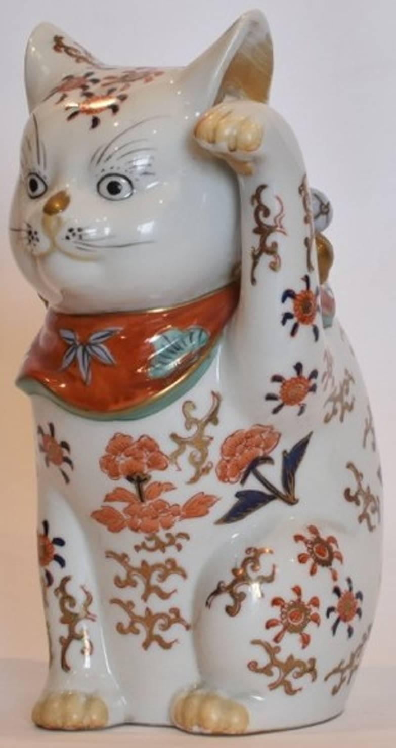 Japanese Imari gilded porcelain Beckoning cat, circa 1935 
This left-handed Japanese beckoning cat (maneki neko) was made and hand painted in Imari circa 1935. 
While the origins of the Japanese beckoning cat (“lucky cat”) motif are unclear,