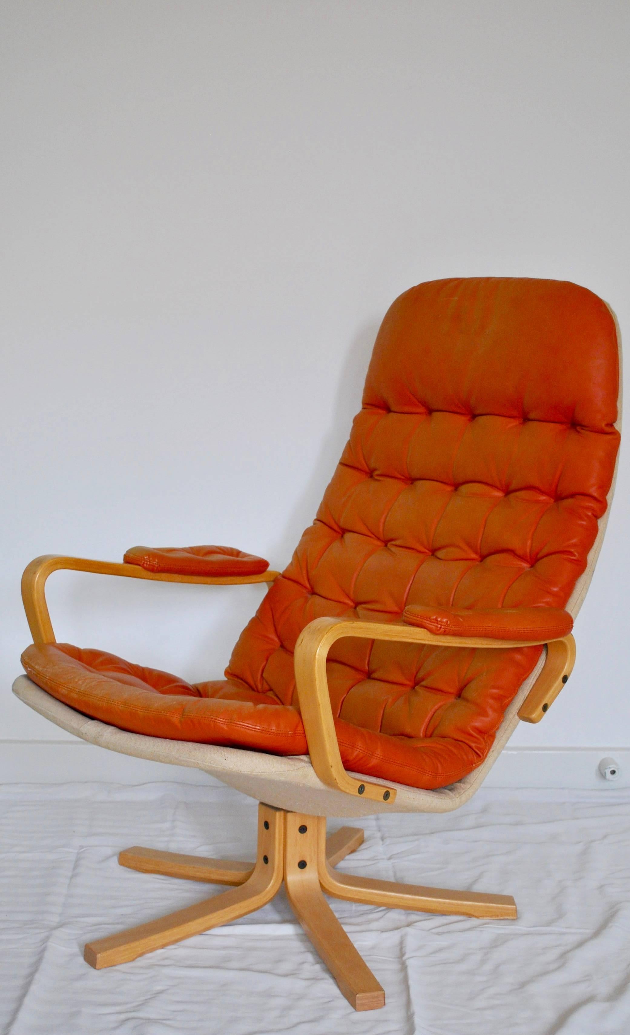 Sam Larsson´s high backed armchair on the swivel stand. 
Cushion covered with deep orange leather and the back with canvas. Armrest and foot of beech. 
Folding leather on leather.
 