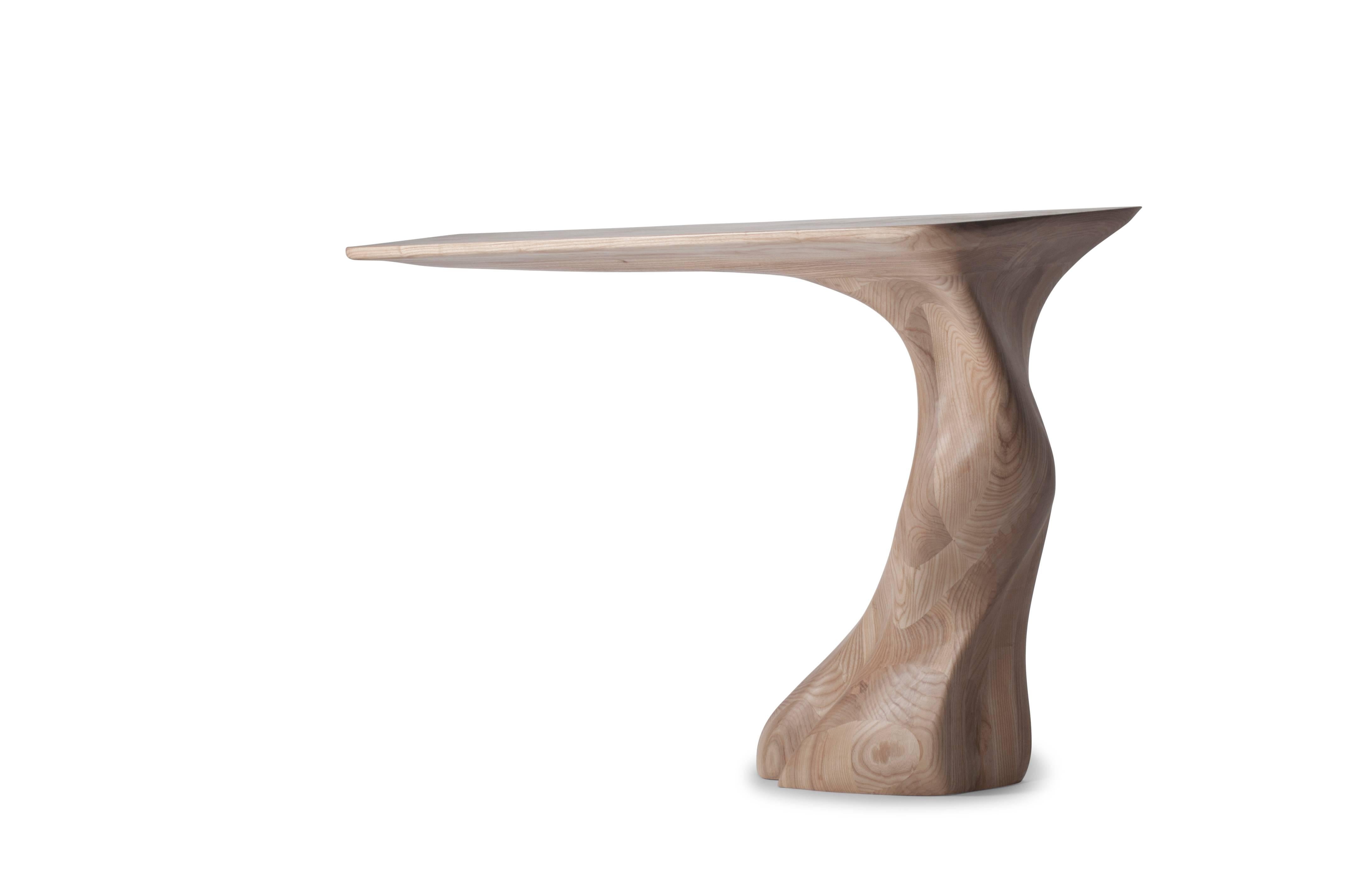 Frolic console table is a stylish futuristic sculptural art table with a dynamic form designed and manufactured by Amorph. Frolic console table is made out of solid ash wood natural stain with natural stained finish. By the nature, the ash wood