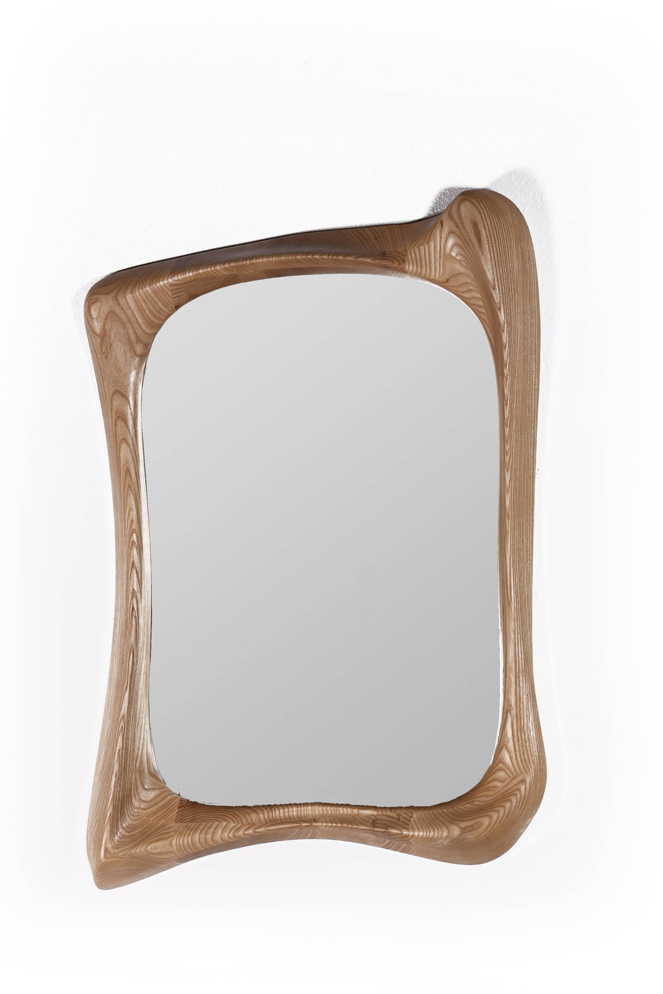 Le miroir Narcissus est un cadre de miroir d'art sculptural futuriste élégant avec une forme dynamique. Nature est fabriqué en bois de frêne massif avec une finition teintée naturelle. Par nature, l'aspect du grain de frêne sera légèrement différent