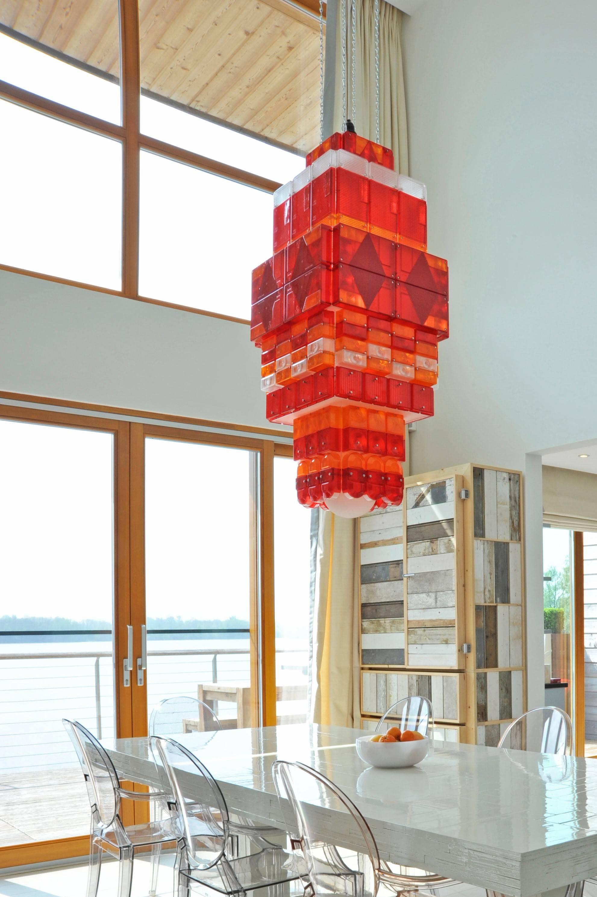 The chandelier is composed of an assortment of tail light covers from vehicles. Haygarth is known for his beautiful assemblages of discarded, mass produced, tonal objects. 

From Stuart Haygarth: 
