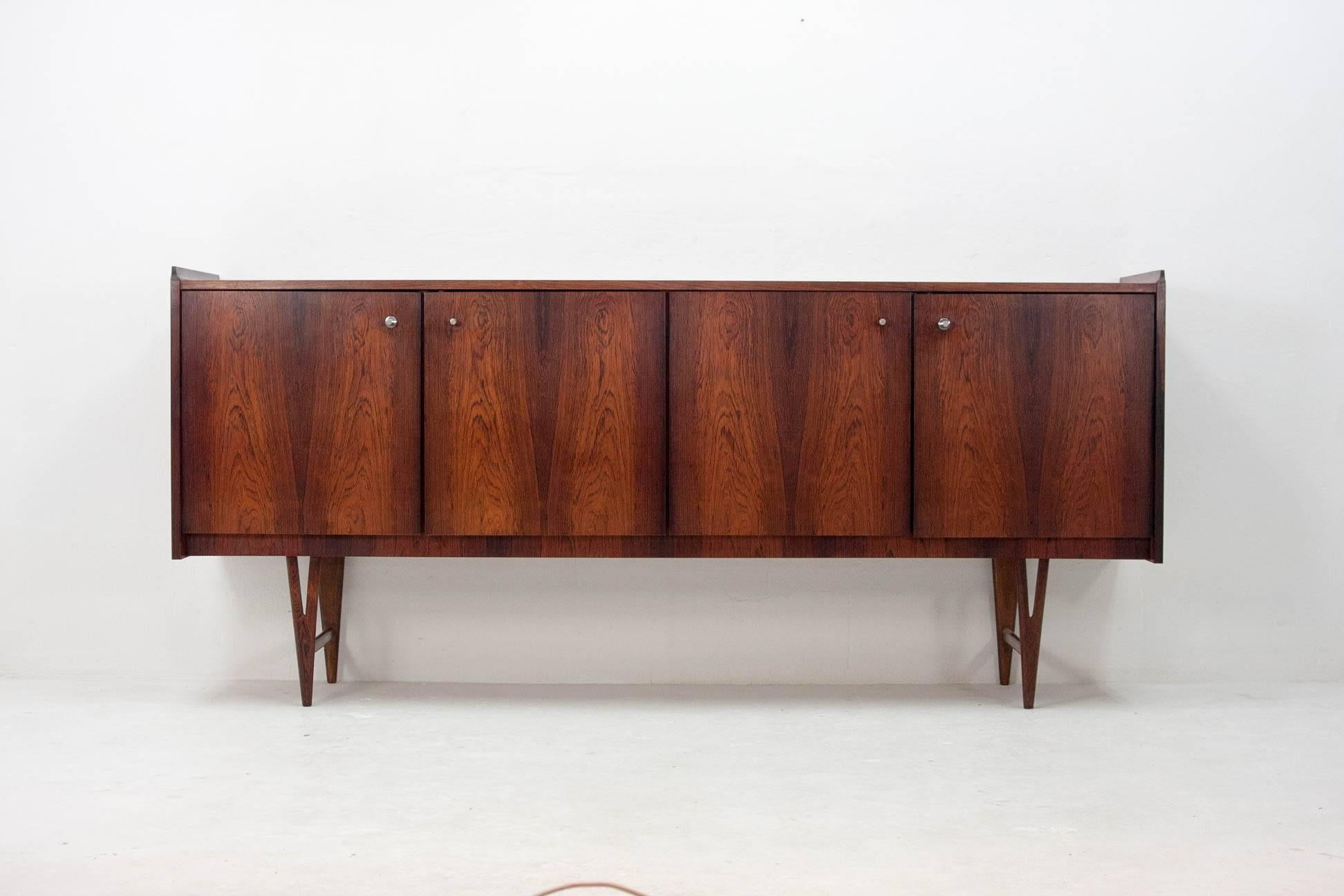 Elegant Fristho sideboard on high legs in rosewood veneer. Built by the Frysian Fristho company in the 1960s. Internally the sideboard is divided into three compartments, a large one on the right side featuring a single shelf and two small ones on