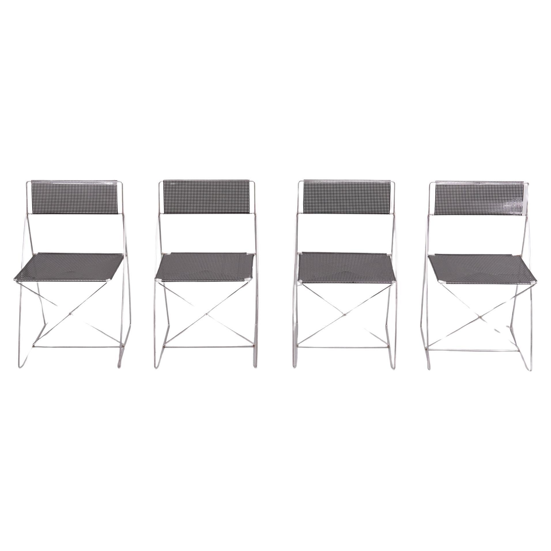 Set of 4 Scandinavian minimalistic stackable Nuova X-line chairs designed by Niels Jørgen Haugesen for Hybodan AS, Denmark, 1970s. Chairs have a chromed steel frame and perforated metal black seating part. The set is in its good original vintage