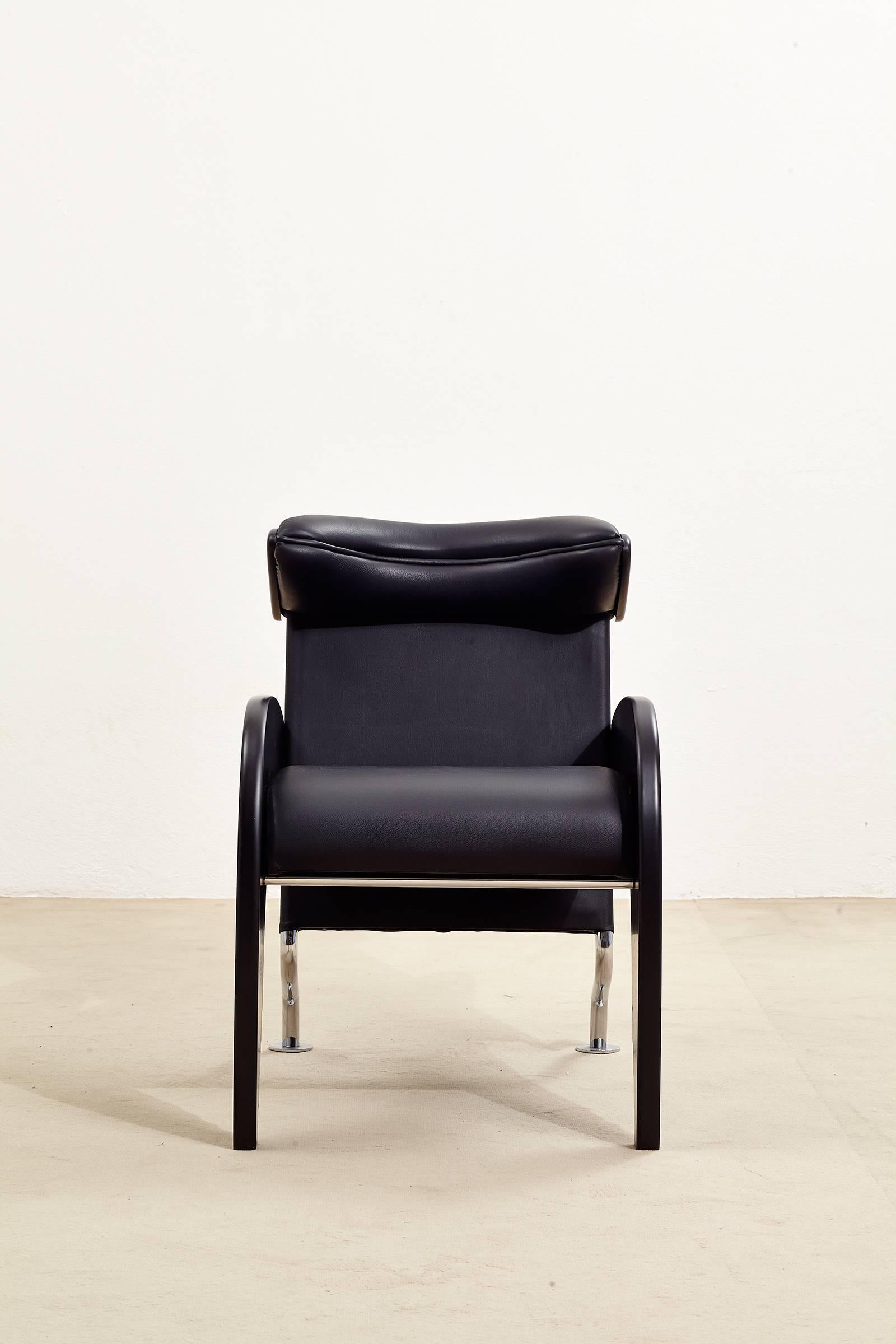 Armchair in wood and metal, upholstered in black leather. The piece clearly expresses the designers interest in dynamism that characterizes much of his work of the 1980s.