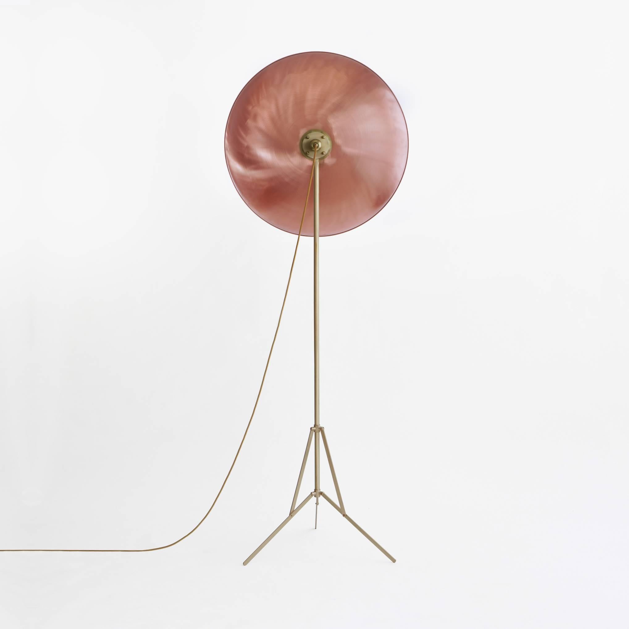 The Parabola copper is a floor lamp with adjustable base in opaque brass and an opaque copper disc. The light generated by the 200 W halogen light bulb is shielded by a smaller central disc, creating a Silhouette which, when the light is on makes it