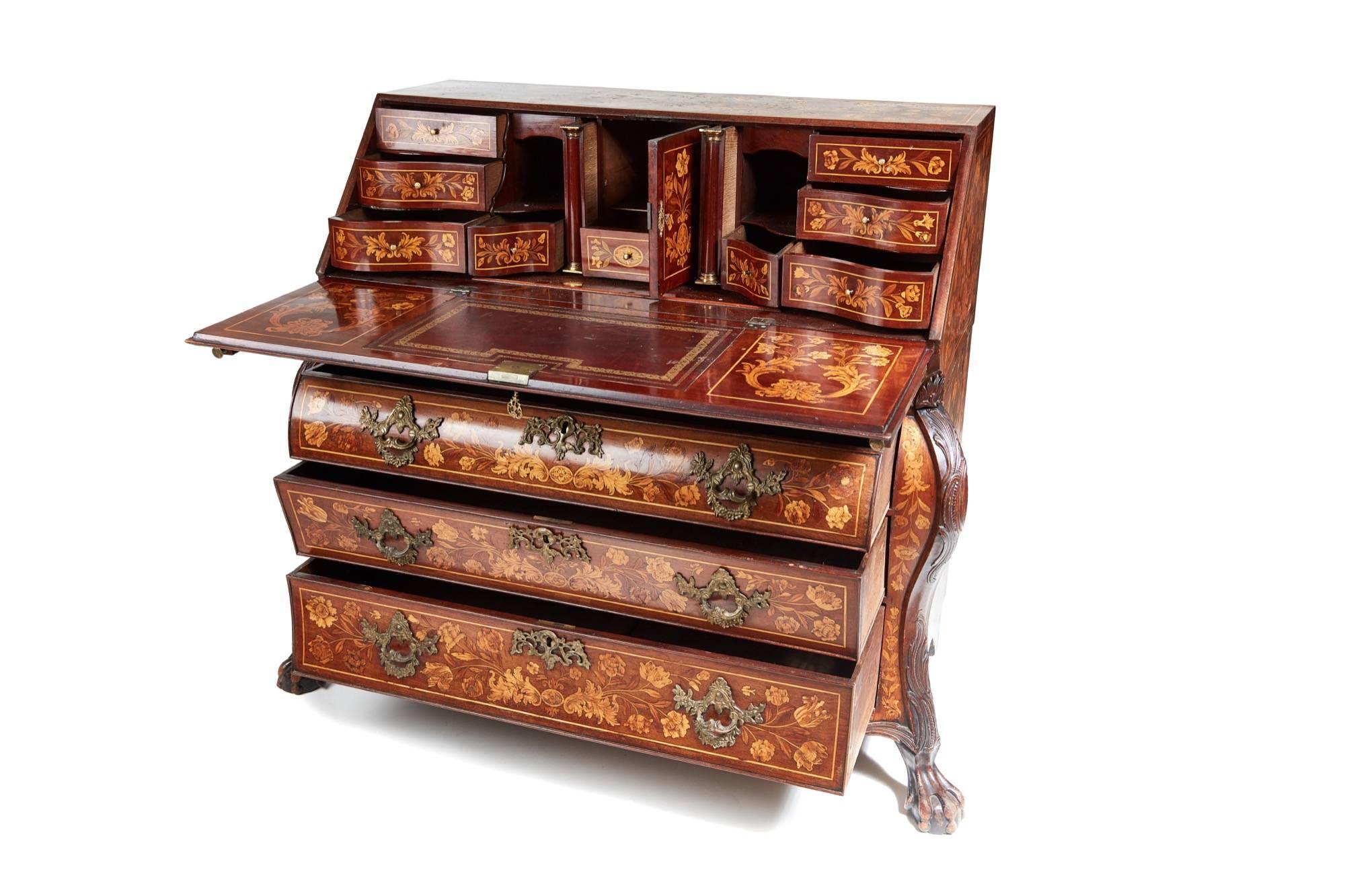 A fine quality 18th century Dutch walnut marquetry bureau with floral inlaid decoration with urns cascading flowers and birds, unusual carving to the fall enclosing a fitted interior of serpentine form with pigeon holes, drawers, bookends, well, and