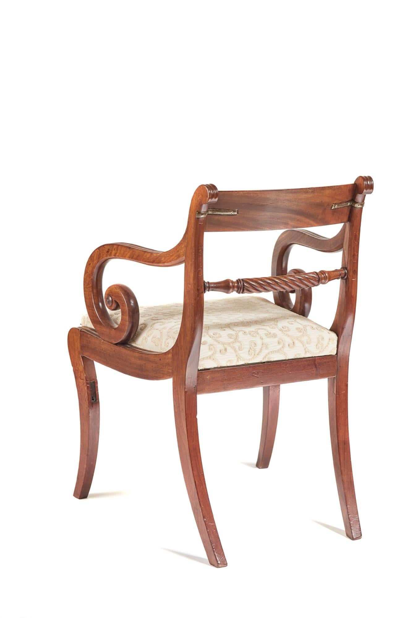 A Regency mahogany elbow chair, with a shaped reeded top rail, twisted rope centre splat, reeded scroll shaped arms, on reeded sabre front legs outswept back legs.

Very old repairs good color.