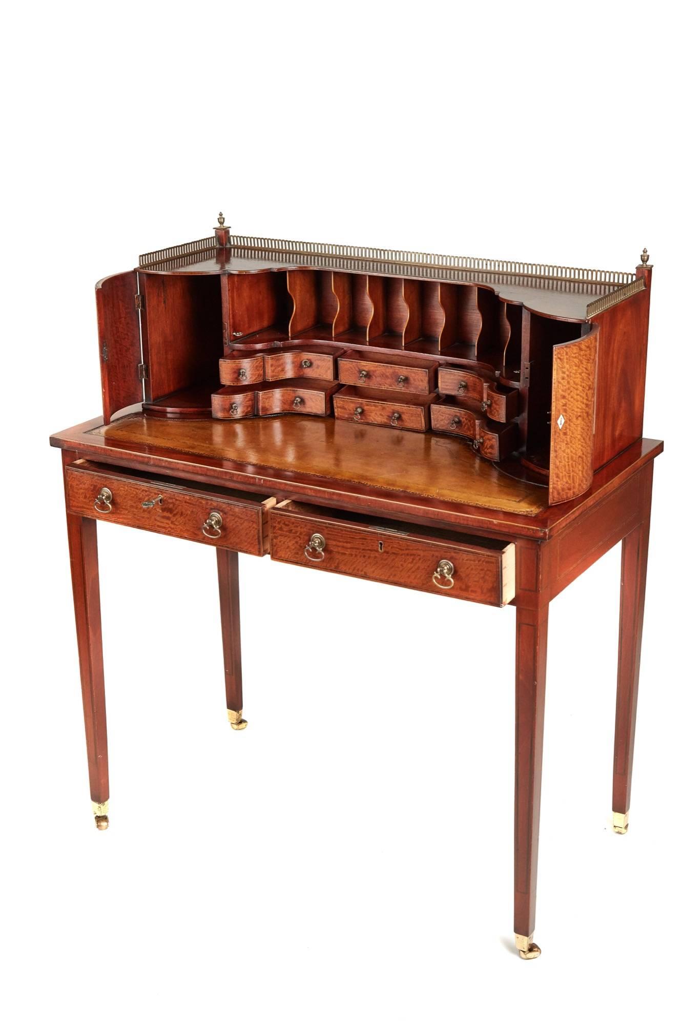 Inlaid Sheraton style ladies writing table, the top having a superstructure with two shaped doors with flame mahogany inlaid outlined in satinwood, six shaped drawers with flame mahogany inlaid outlined in satinwood with eight pigeon holes with