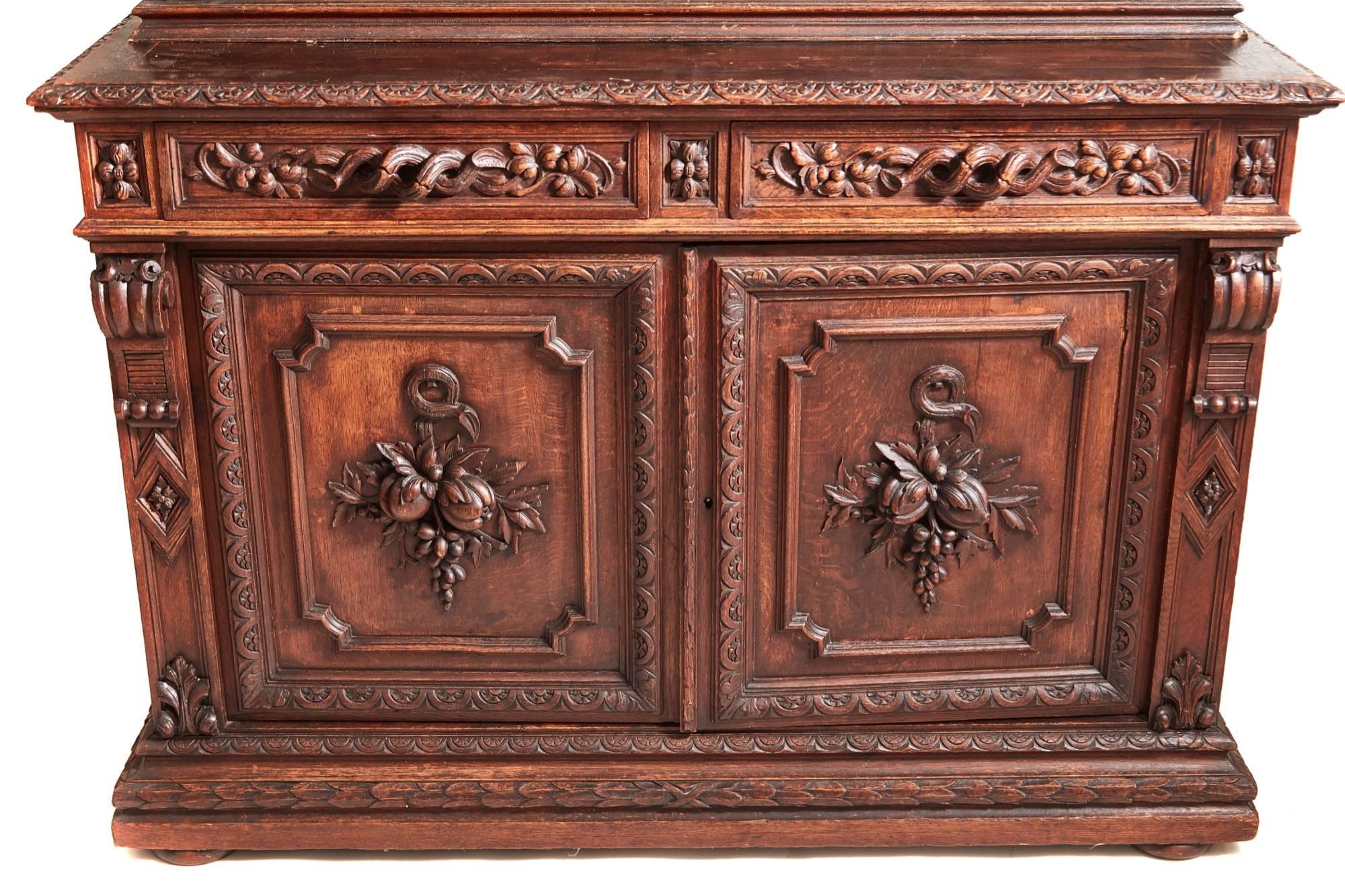 A superb antique heavily carved oak bookcase, the upper section having a carved shaped cornice, heavily carved frieze, two glazed doors, flanked by carved mouldings, four adjustable shelves to the interior, lovely carved sides, the base section