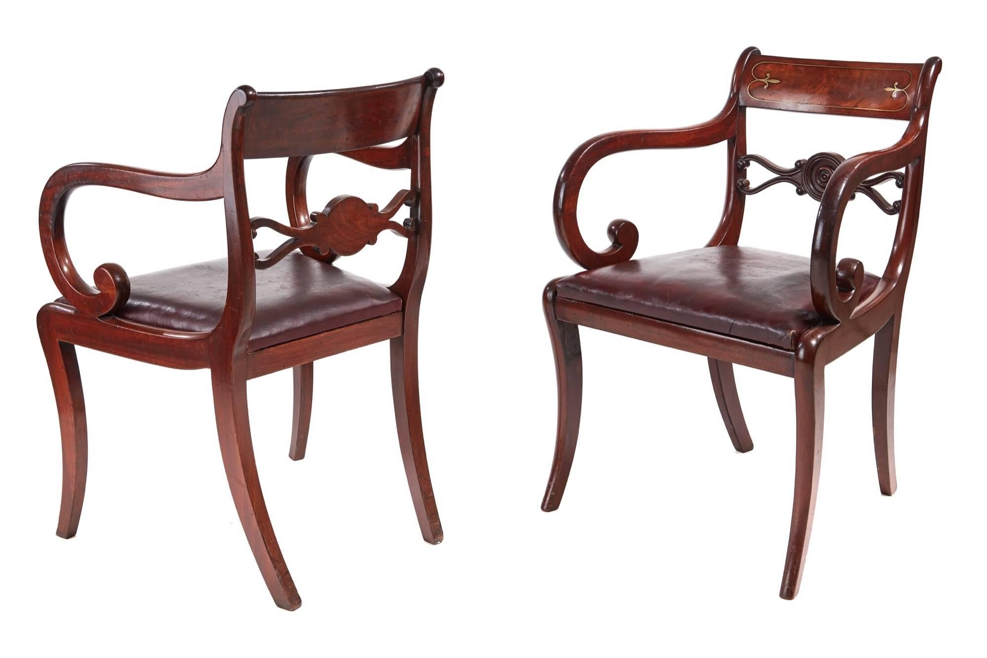 Fine pair of Regency mahogany brass inlaid elbow chairs, with a shaped brass inlaid top rail, shaped and carved centre splat, scroll shaped arms, drop in seat, standing on sabre legs
Lovely original color, one old repair to front leg.
