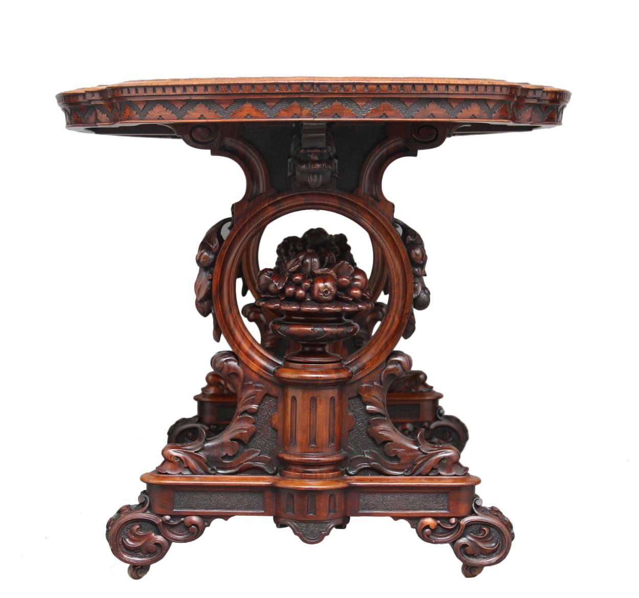 Outstanding exhibition quality burr walnut centre table, the finely carved end supports incorporating a carved bowl of fruit and flowers with in a circle with hanging fruit, he highly burr walnut quarter veneered top also has a carved edge