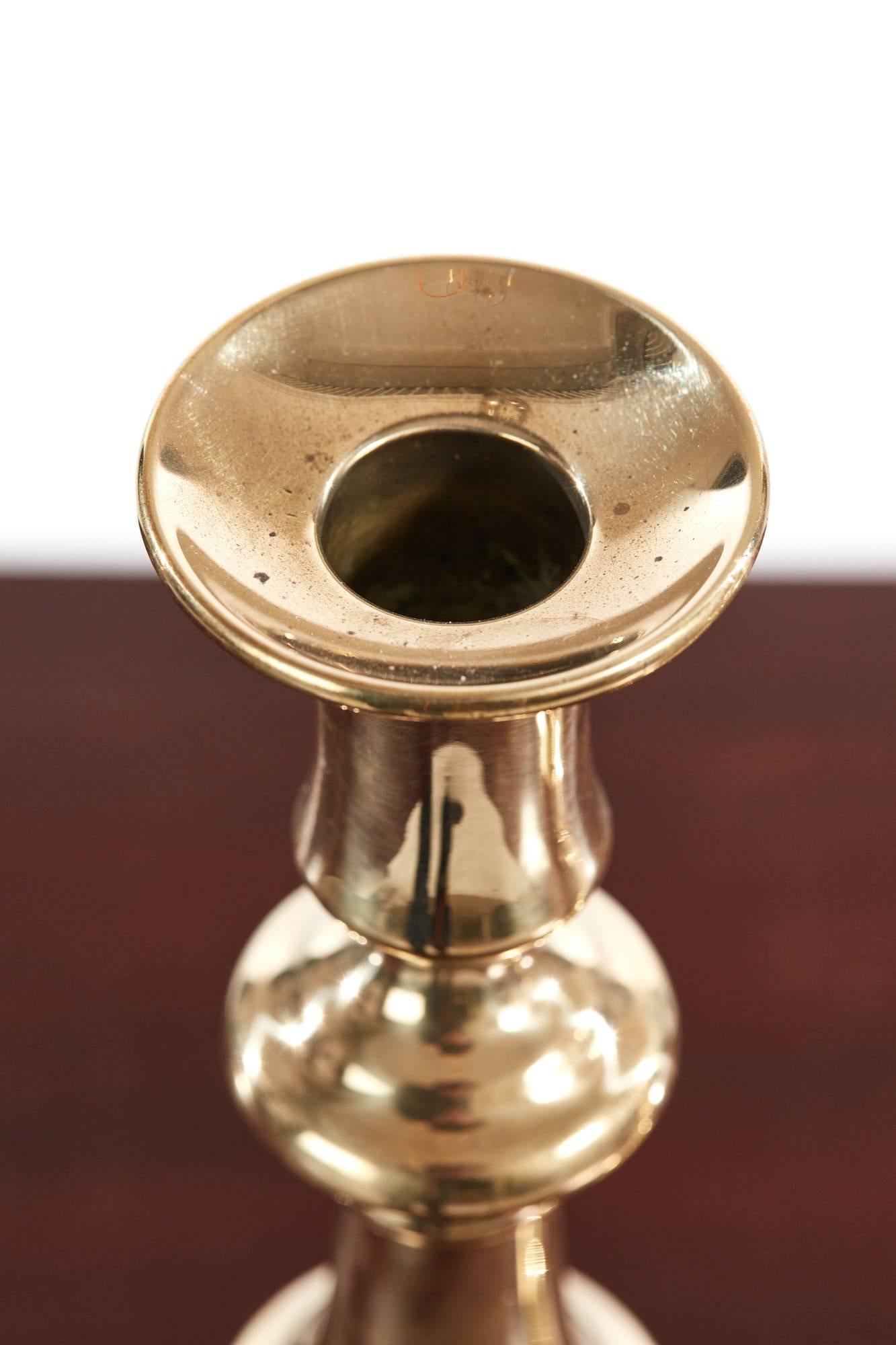 Pair of antique brass candlesticks, with a shaped tapering column, rising from a stepped round base, each candlestick still retains its original push ejector rod.
