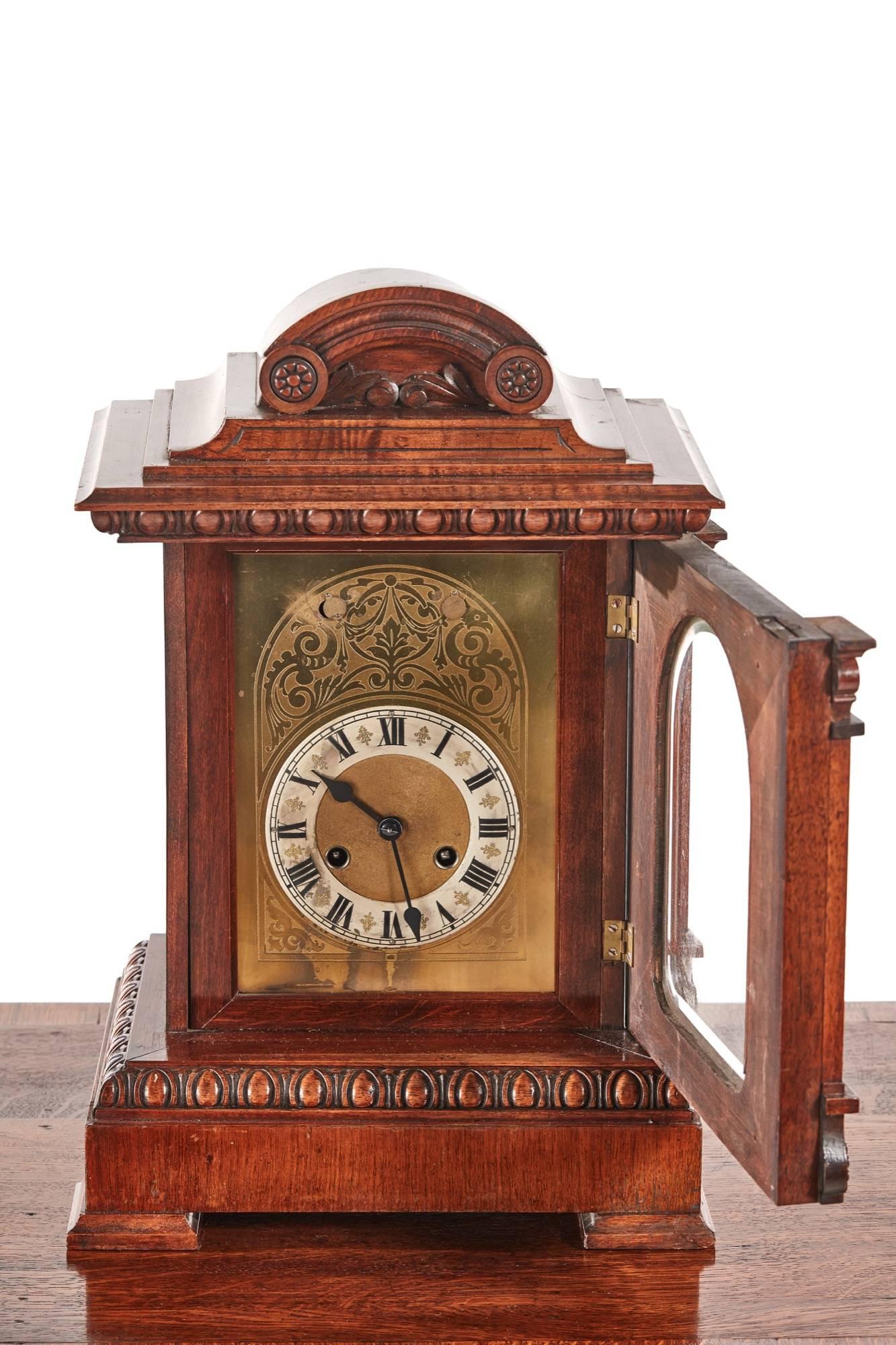 Antique carved walnut mantel clock, of architectural style with an arched pediment, the dial flanked by Corinthian columns above a carved frieze and plinth base, the brass and silver dial with roman numerals,8 day chiming movement signed [junghans]