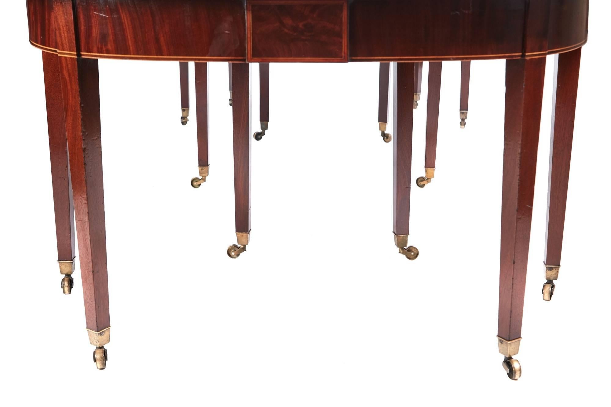 Fine George III mahogany dining table, having a fantastic solid mahogany top with a reeded edge, lovely inlaid frieze, drop leaf table to the centre, standing on 14 square tapering legs with original brass castors, all original
This table also