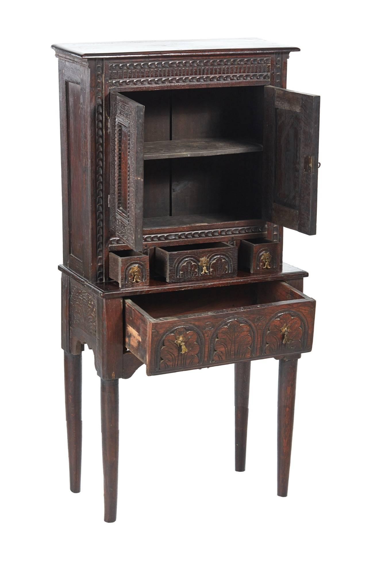 Small antique carved oak cupboard, top section with a carved frieze two carved doors and three carved drawers all with original brass handles, the base with one long carved drawer original brass handles, carved ends, standing on turned legs
Lovely