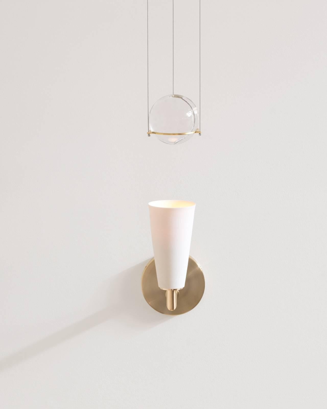 Grace is a contemporary union of softness and structure. A porcelain and brass-mounted light illuminates and engages an artfully suspended blown glass sphere.

Details:

Glass sphere blown by John Hogan.

Wheel-thrown porcelain shade by Lilith