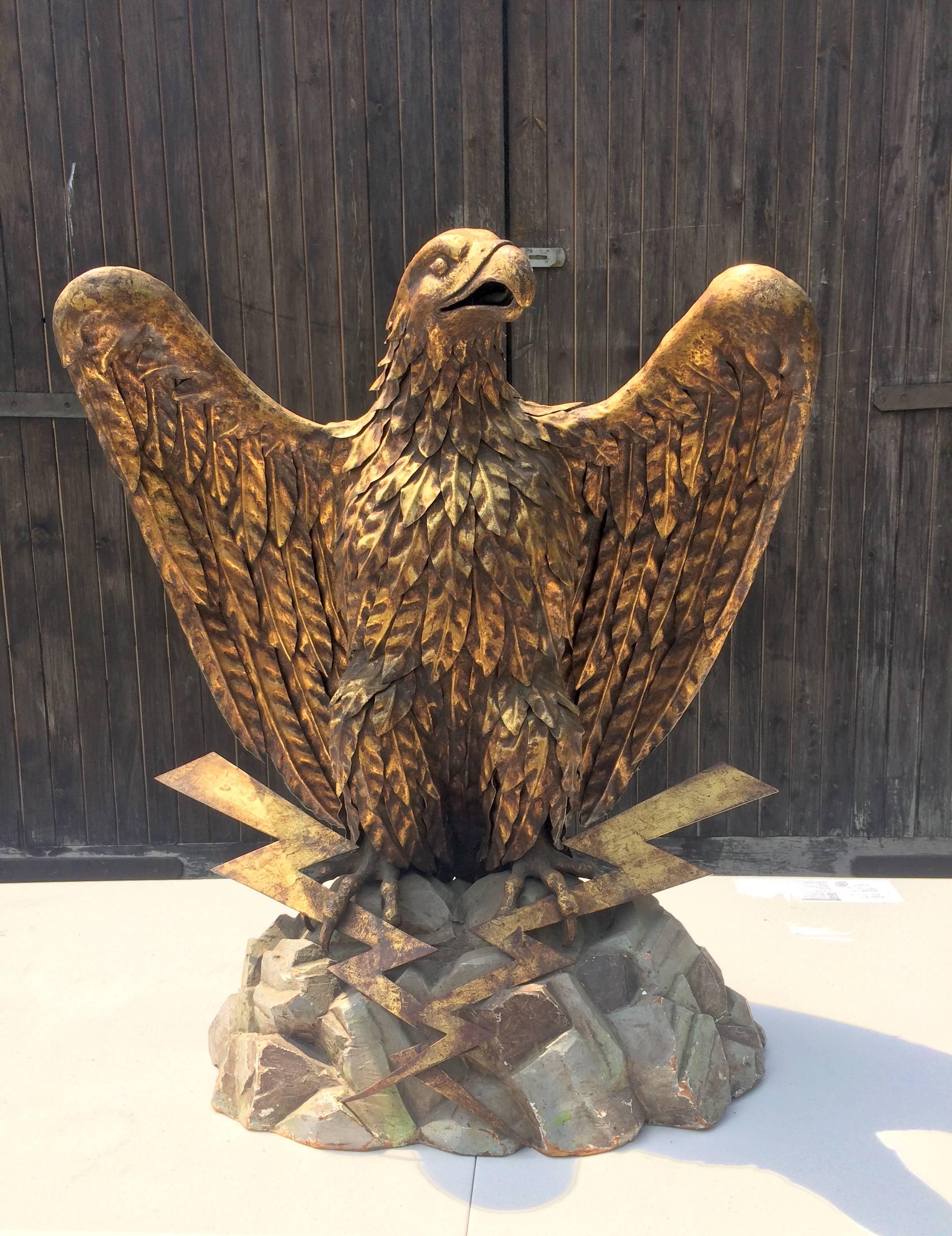 Large Italian eagle clad in patinated metal feathers, mounted on a wooden rock shaped base with lightning bolt metal arrows to the front. There is a metal plate under the base that reads S. Salvadori, Firenze 1955. It measures 32 inches (82cm) high.