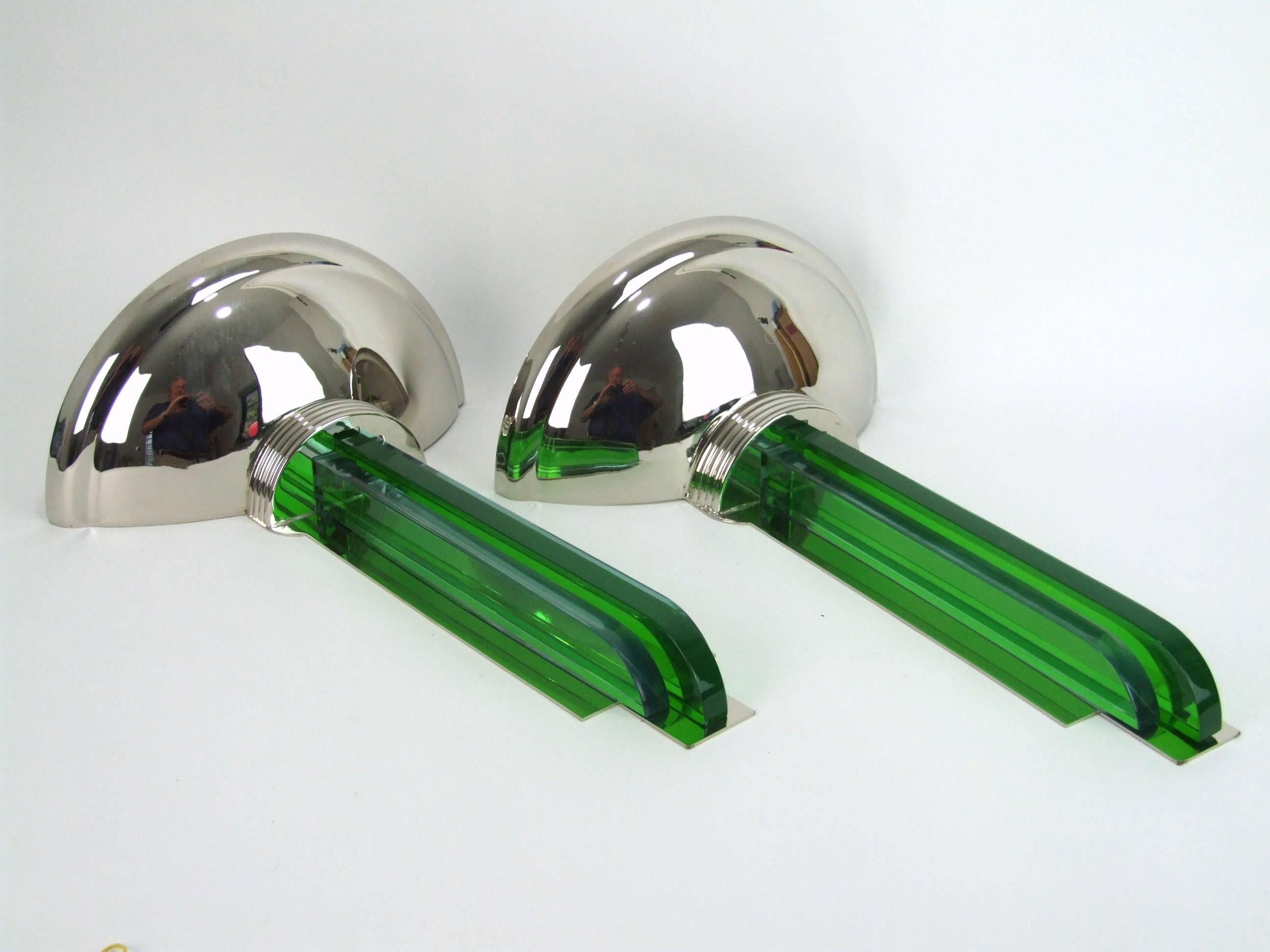 A pair of contemporary modernist Art Deco style wall lights. Chromed metal cup uplighter with green glass central shards within a pair of clear glass shards that echo the light down the wall reflected by the chromed metal back panel. They each
