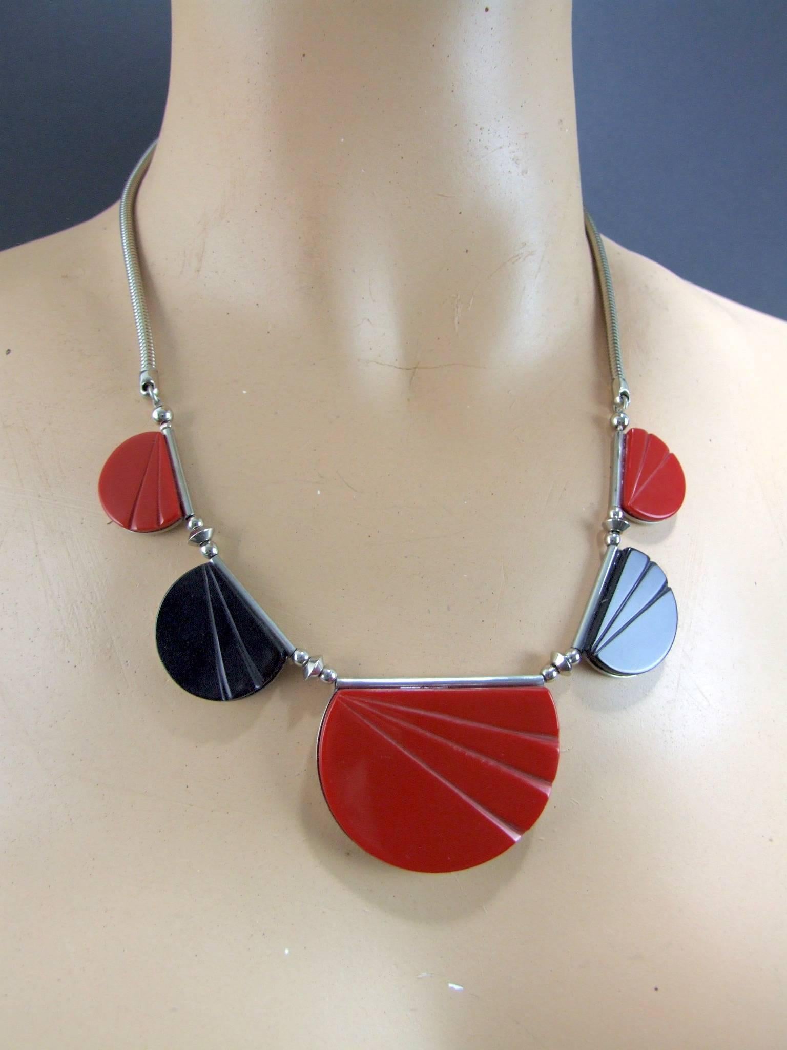 A German galalith and polished metal necklace in red and black carved galalith panels made in the early 1930s. The centre red galalith section measures 1.5 inches high by 2 inches wide. Total length from clasp to clasp is 19.5 inches (49cm). In