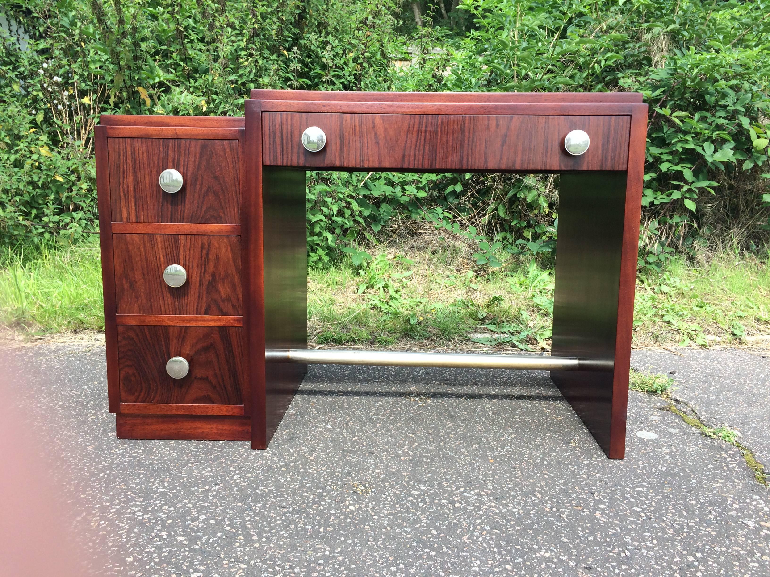French Rosewood desk with one knee hole drawer and three side drawers. Chrome footrest to the base and silvered bronze drawer handles. Condition is very good as recently renovated. It measures 41.5 inches wide by 21.5 inches deep by 28 inches high