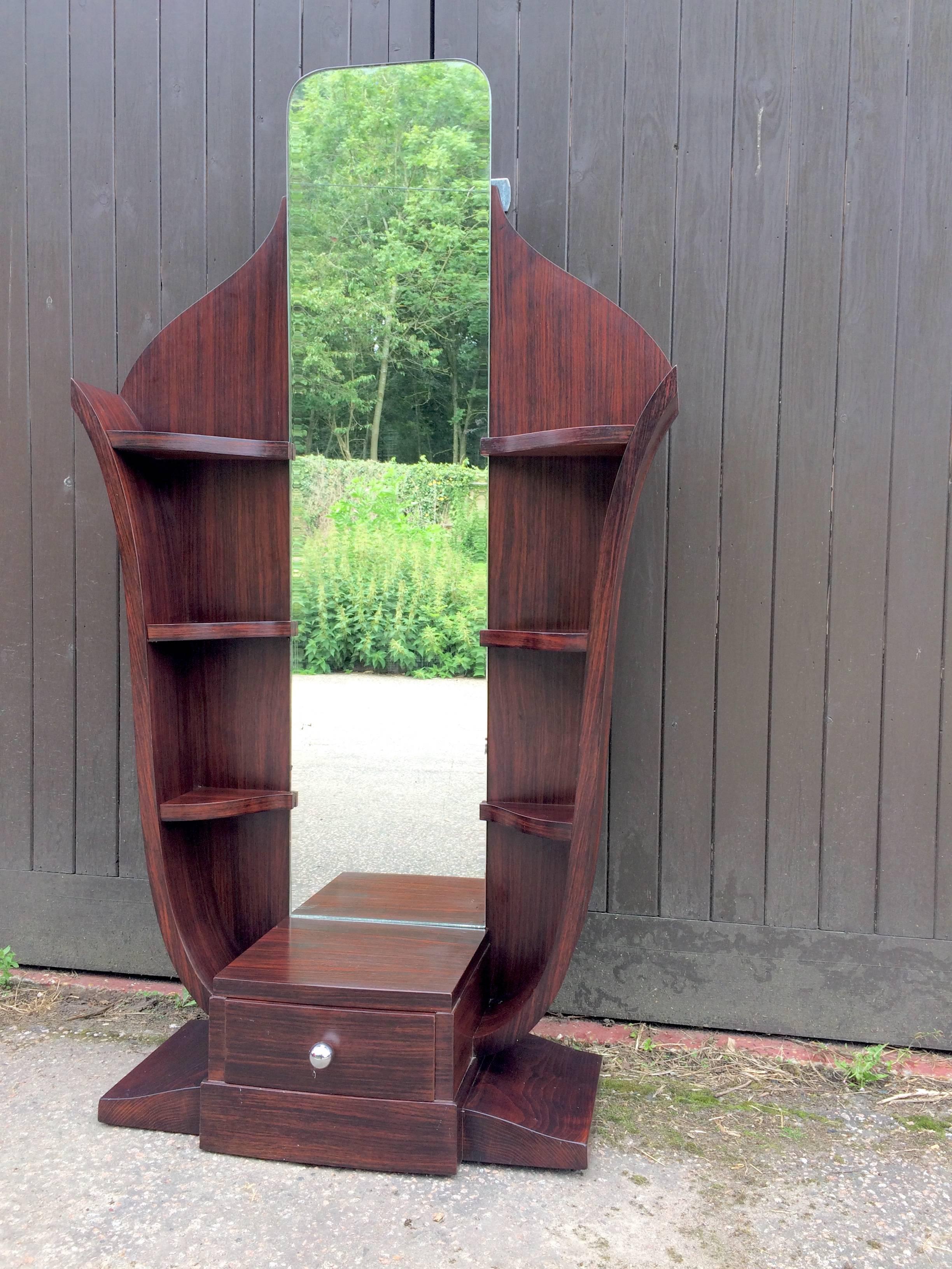 Macassar ebony stand and mirror, apparently known as a psyche mirror. Three Display shelves down each side of the mirror and a central lower drawer over the shaped plinth with a chromed metal handle. Could be used as a hall stand. Excellent