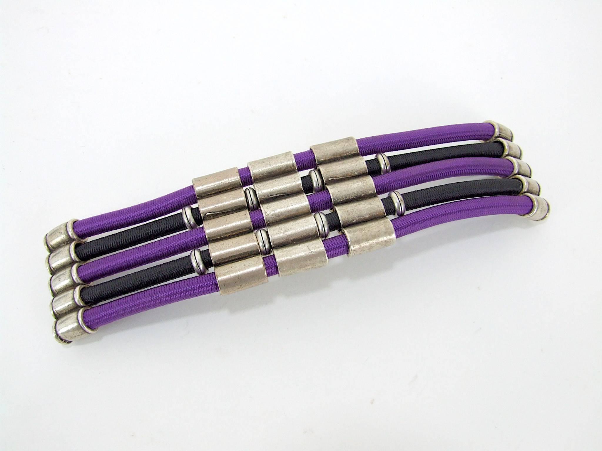 French Art Deco style purple and black cord and metal bangle by Max Debraine. Unsigned and It measures 7.75 inches long by 2 inches wide (19.5cm x 5cm). It will fit a small to medium sized wrist and is elasticated. It fixes together by means of a