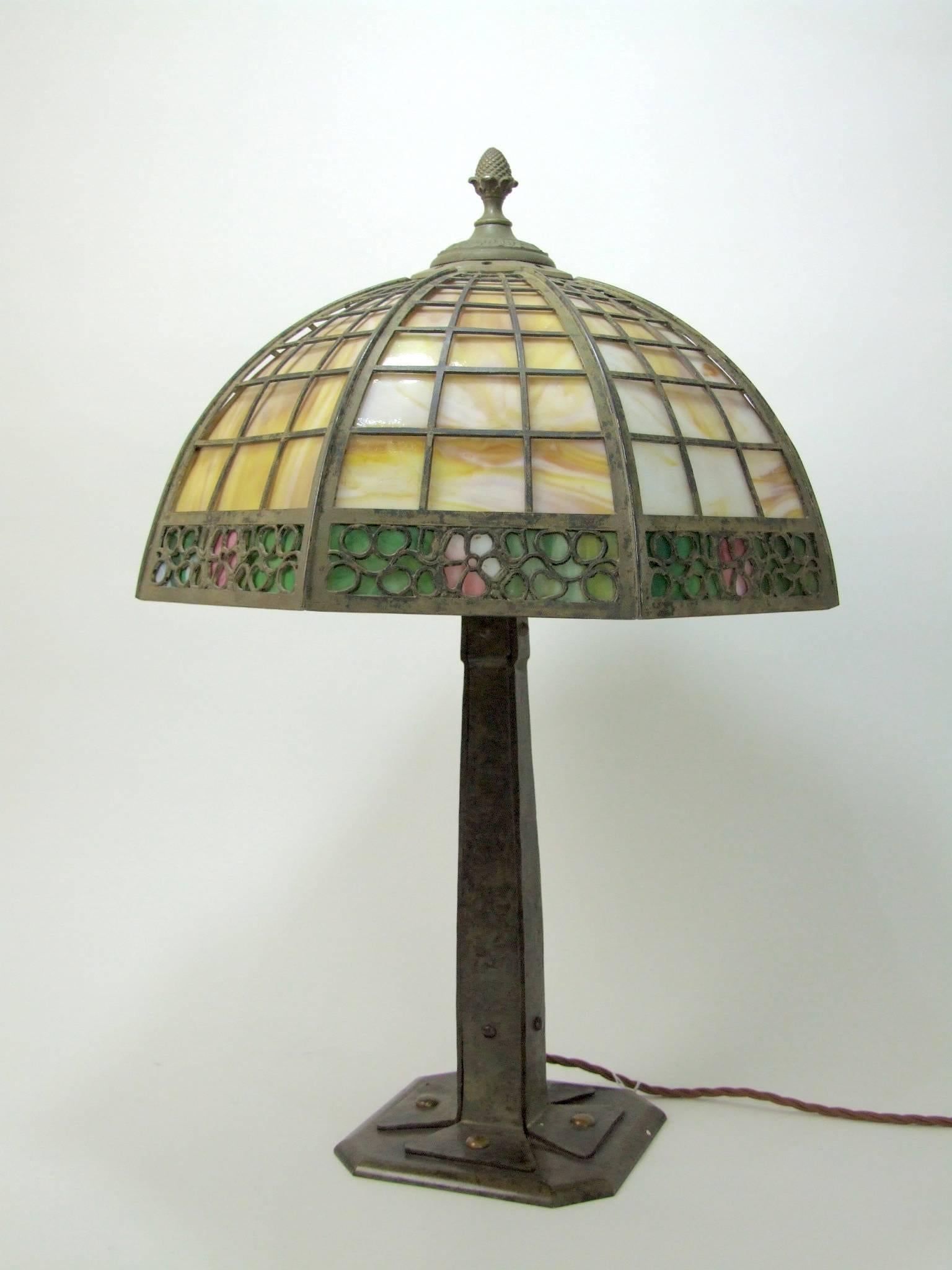 Large Miller/Tiffany Studio style metal lamp of either green patinated bronze or wrought metal with pâte de verre glass panel shade. Date unknown but appears to be of some vintage and in the Mission style and definitely not a modern reproduction. A
