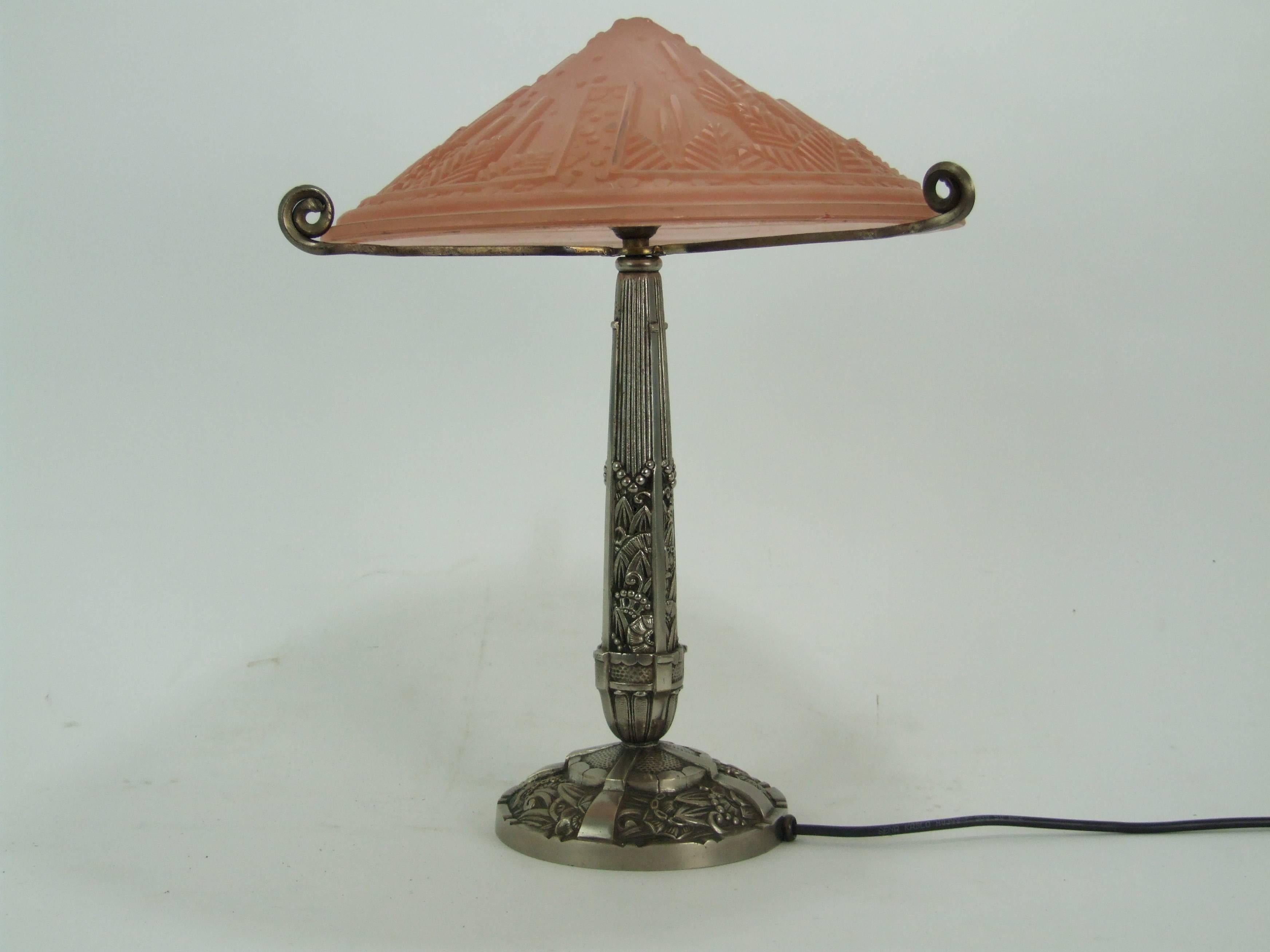 French Art Deco stylized floral silvered bronze Art Deco table lamp. Unsigned but undoubtedly Muller Frere. Peach glass moulded dome shade. It measures 16 inches high 13.5 diameter to the shade (41cm x 34cm). Condition is very good with one very