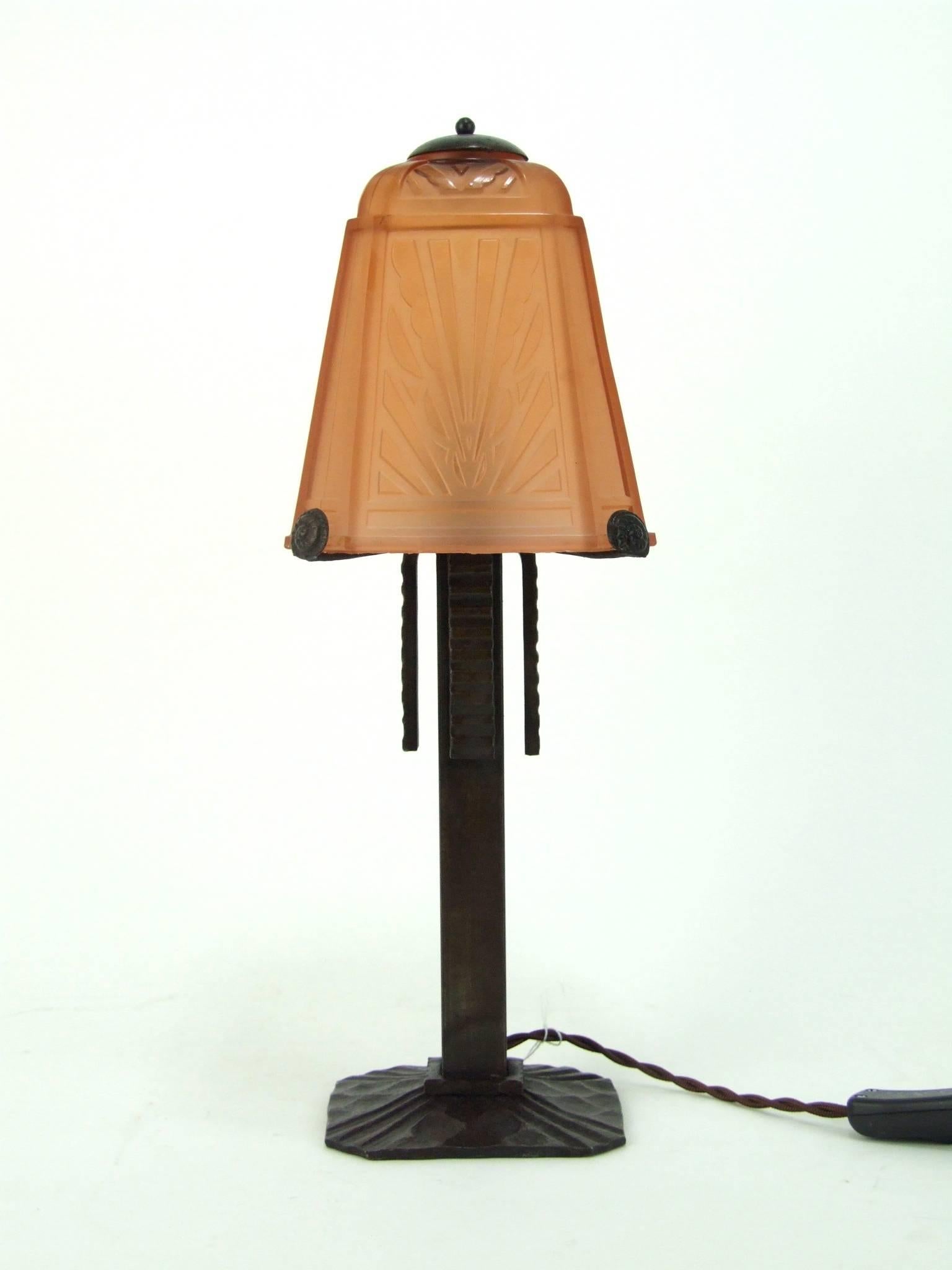 Table lamp by Muller Freres. 
French Art Deco fer forge (wrought iron) table lamp with peach glass sun ray shade by Muller Freres. It measures 15.5 inches high by 5.5 inches wide by 5.5 inches deep (40cm x 14cm x 14cm). Apparently unsigned by