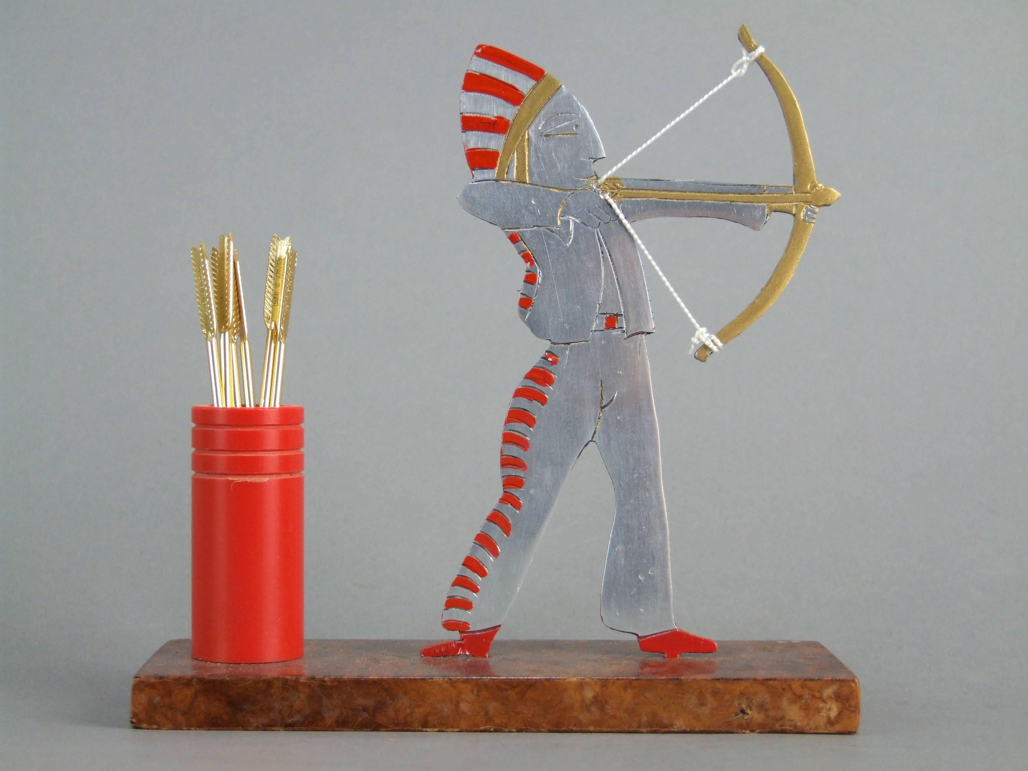 An unsigned cocktail sticks set, another in the catalogue of Raymond Sudre. Mounted on an amboyne wood base with a polished aluminium American Indian with his bow and complete set of six gilt arrow cocktail sticks. Measures: Height: 5 inches (13cm),