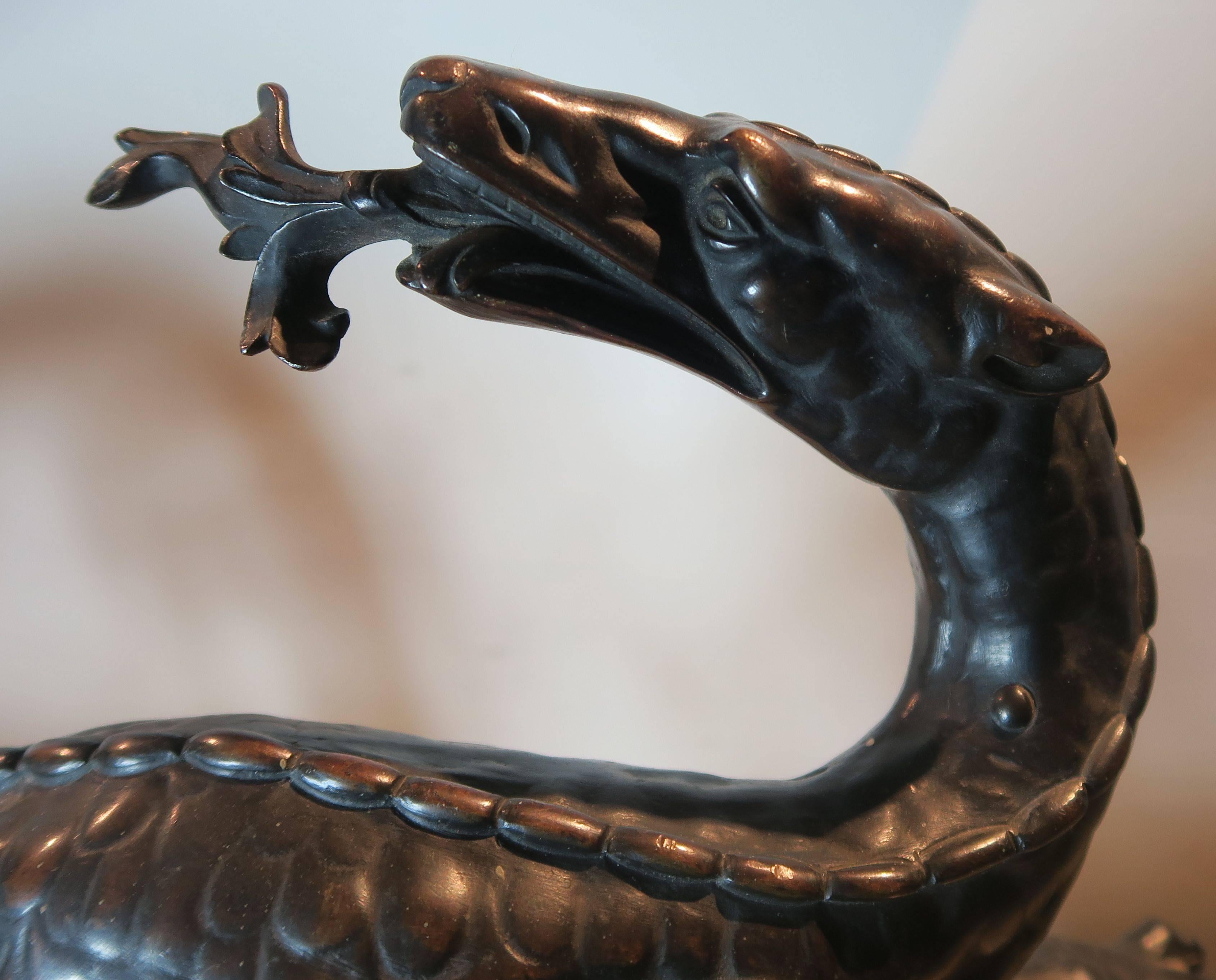 A pair of French 18th century patinated bronze dragons mounted on partial giltwood bases.