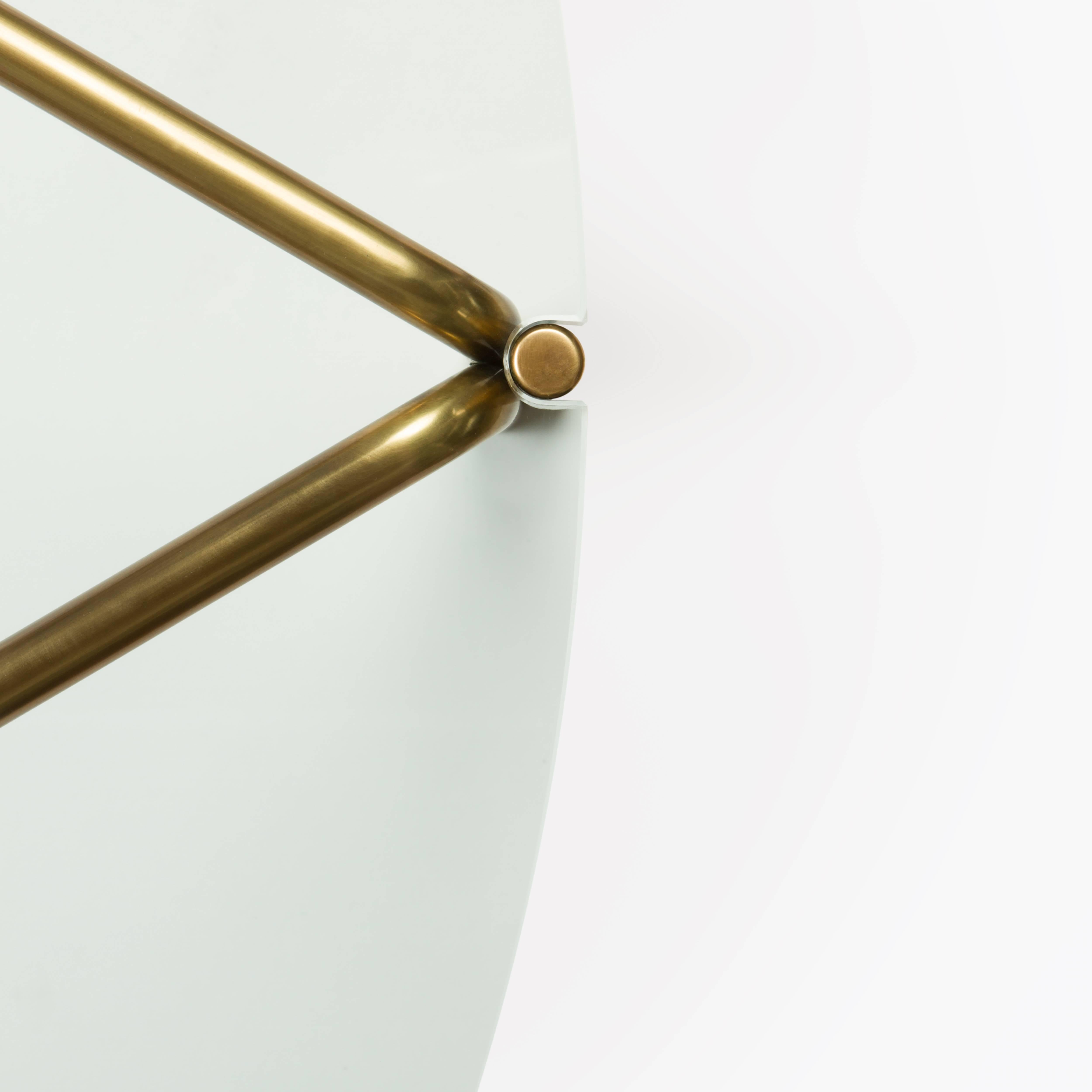 The CA4G series of tables is intended to be understood geometrically, as the round tops circumscribe triangulated frames below. 

Available in several custom material and finish options, tempered glass top / polished, unlacquered brass frame and