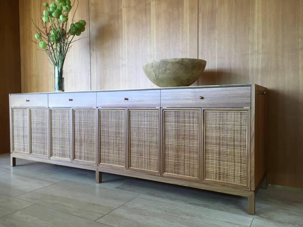 Inspired by the classic midcentury, this solid teak buffet is perfectly suited for a modern interior. A textured solid brass top complements the subtle brass and cane details of the door faces. Blum glides are concealed below the dual solid teak
