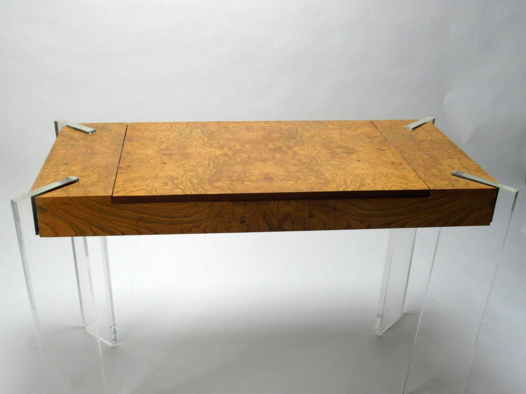 Burled Olive & Lucite game table by Vladimir Kagan. This all original example has four inset solid Lucite legs and a burled olive wood case. Top center panel removes to reveal inset backgammon board with bakelite game pieces, leather suede