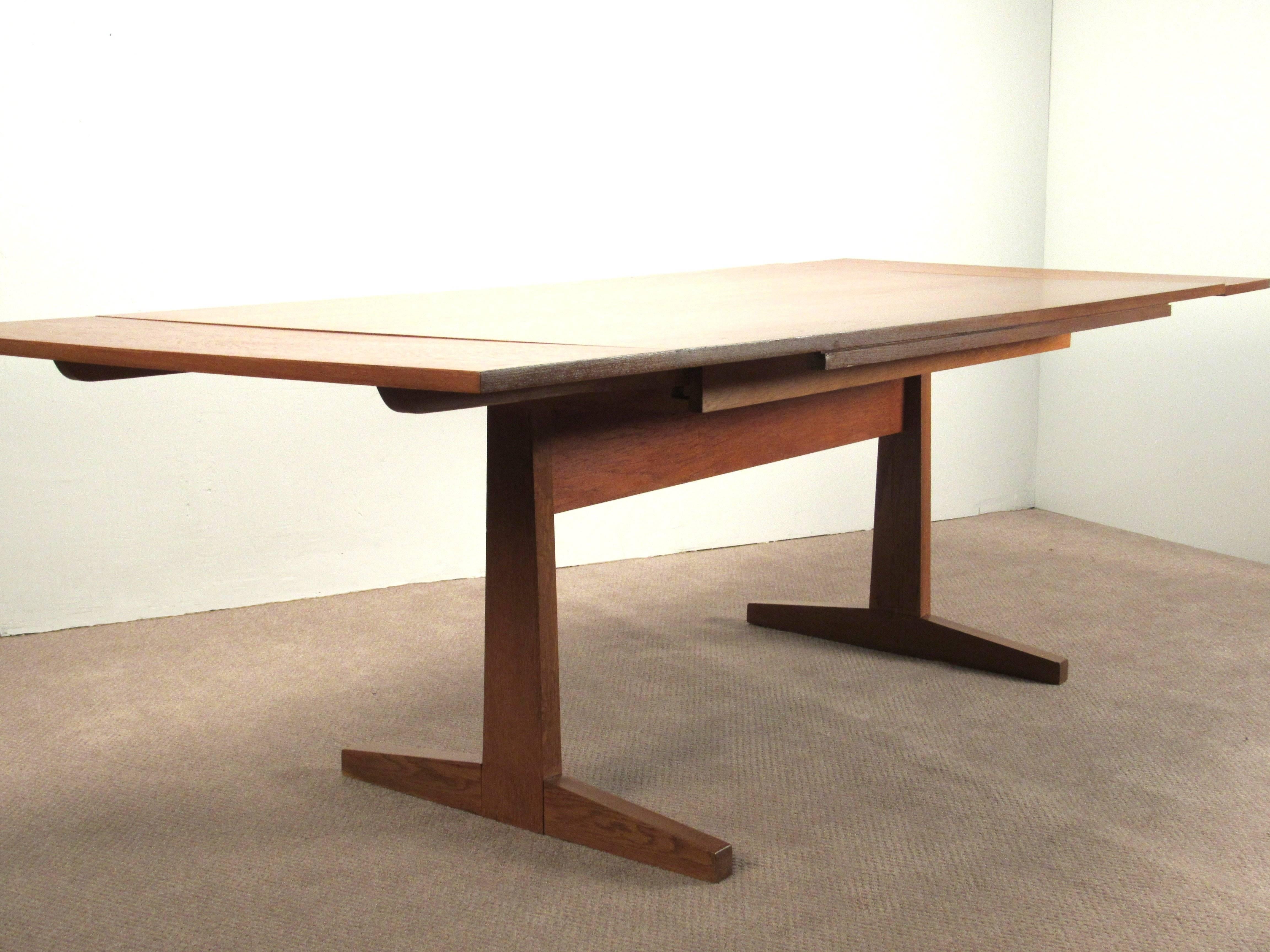 Danish Modern Teak Extending Dining Table with Pedestal Base, 1960s.   Teak Table with leaves that extend from both ends of the table and slide underneath for storage.  
  
Table is 72