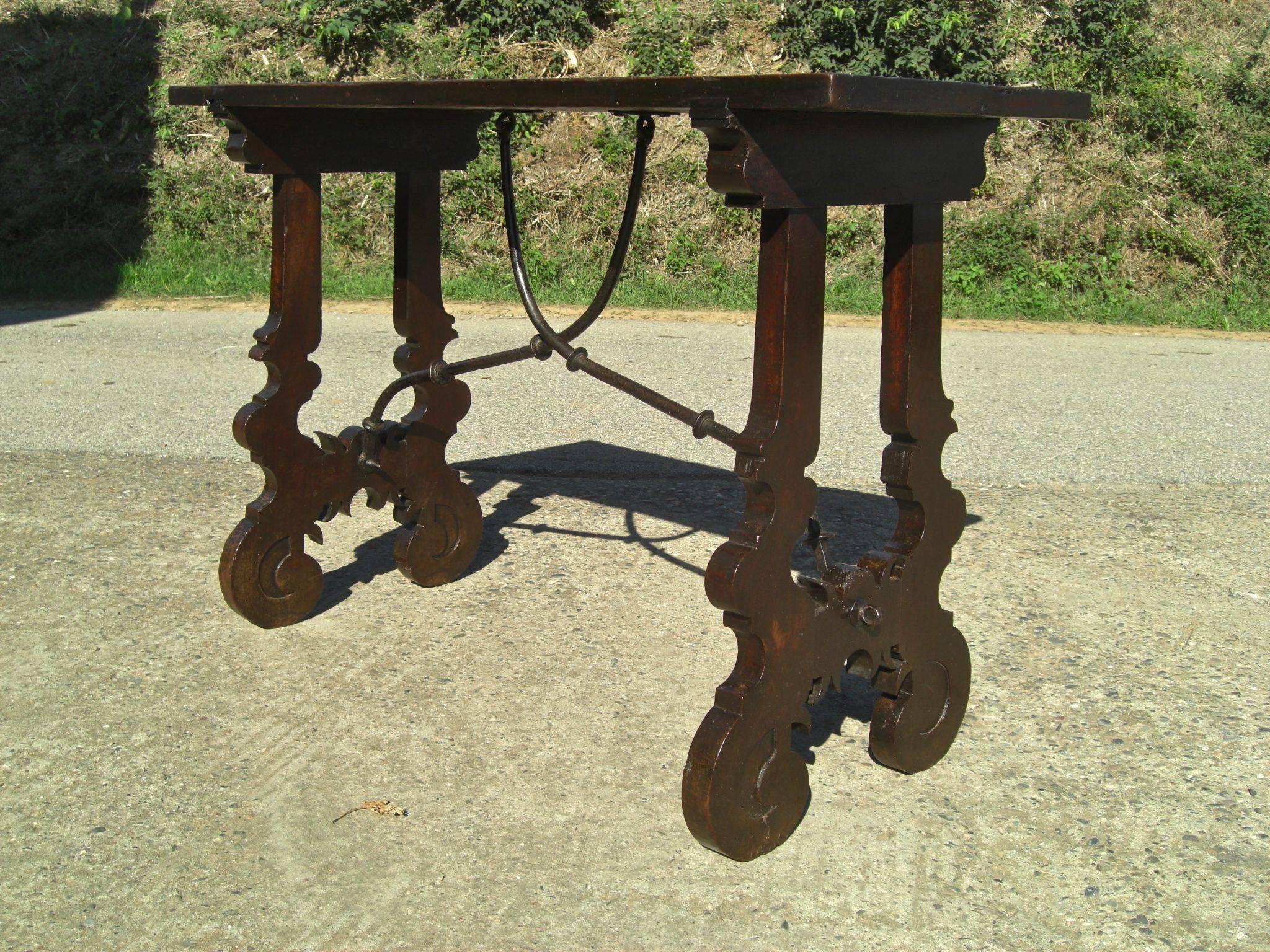 This delicately proportioned walnut console table features a single board top, beautifully scalloped lyre legs, its original wrought iron stretchers and lustrous 