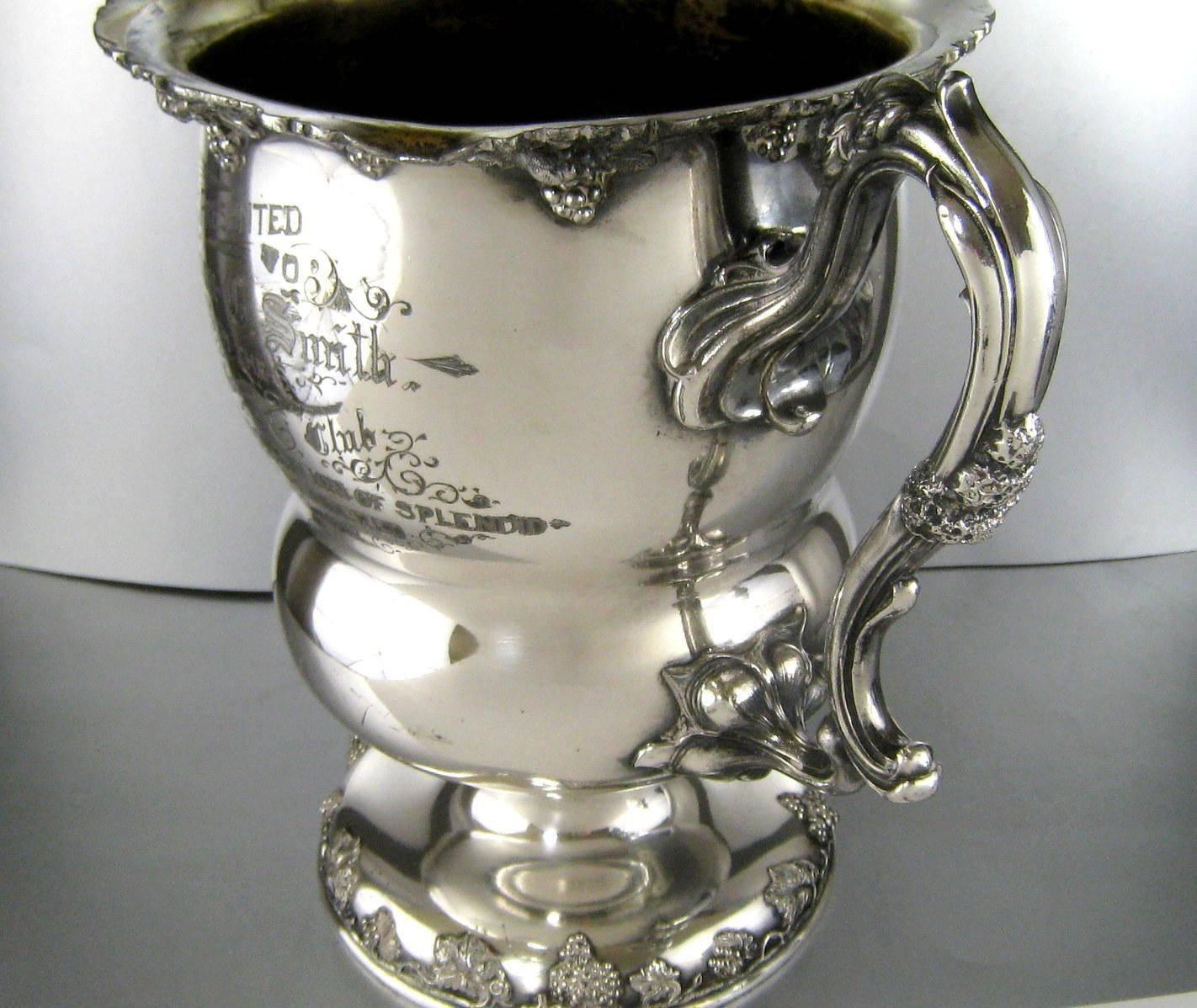 Wonderful and large antique silver plate trophy wine cooler. The trophy is decorated with a dimensional grape and vine around its rim and foot. The handles are designed as stylized grape vines. Marked on the bottom as made by the Barbour Silver Co.