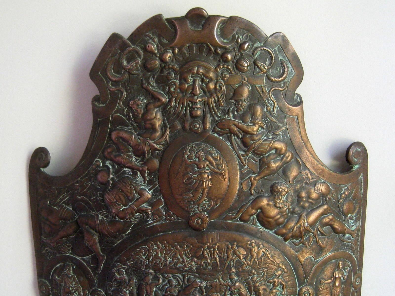 This beautifully detailed cast iron shield is decorated in Renaissance style. I have not identified the original, but I imagine this piece is a copy of a known parade shield. The finish is a glowing coppery bronze with darkened patina and verdigris.