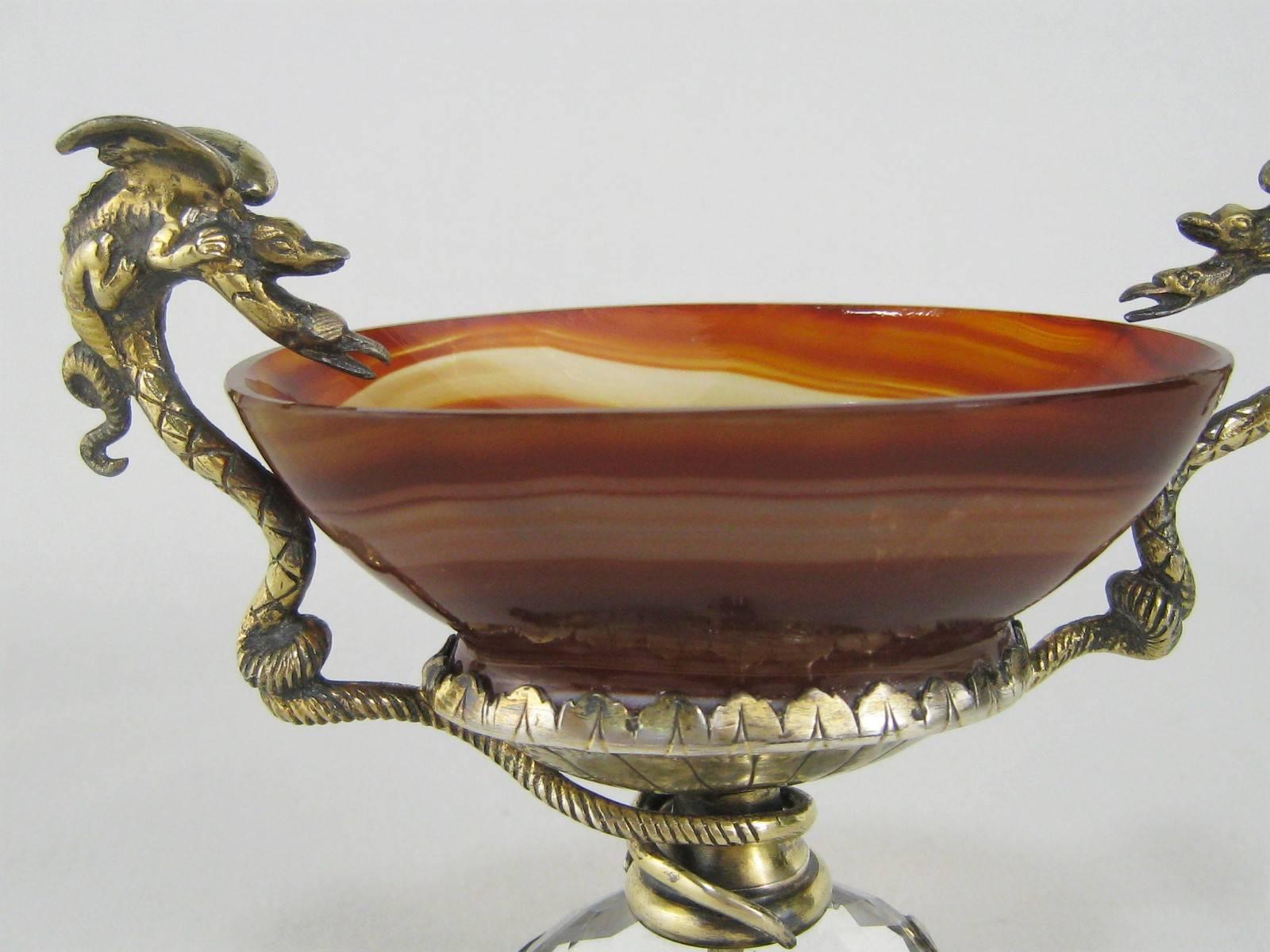 This beautiful and unusual salt dish is carved of red banded agate stone. It sits atop a gilt silver and faceted rock crystal base with four tiny frogs as feet. Turquoise stones are mounted on each side. The bowl is supported by handles cast as