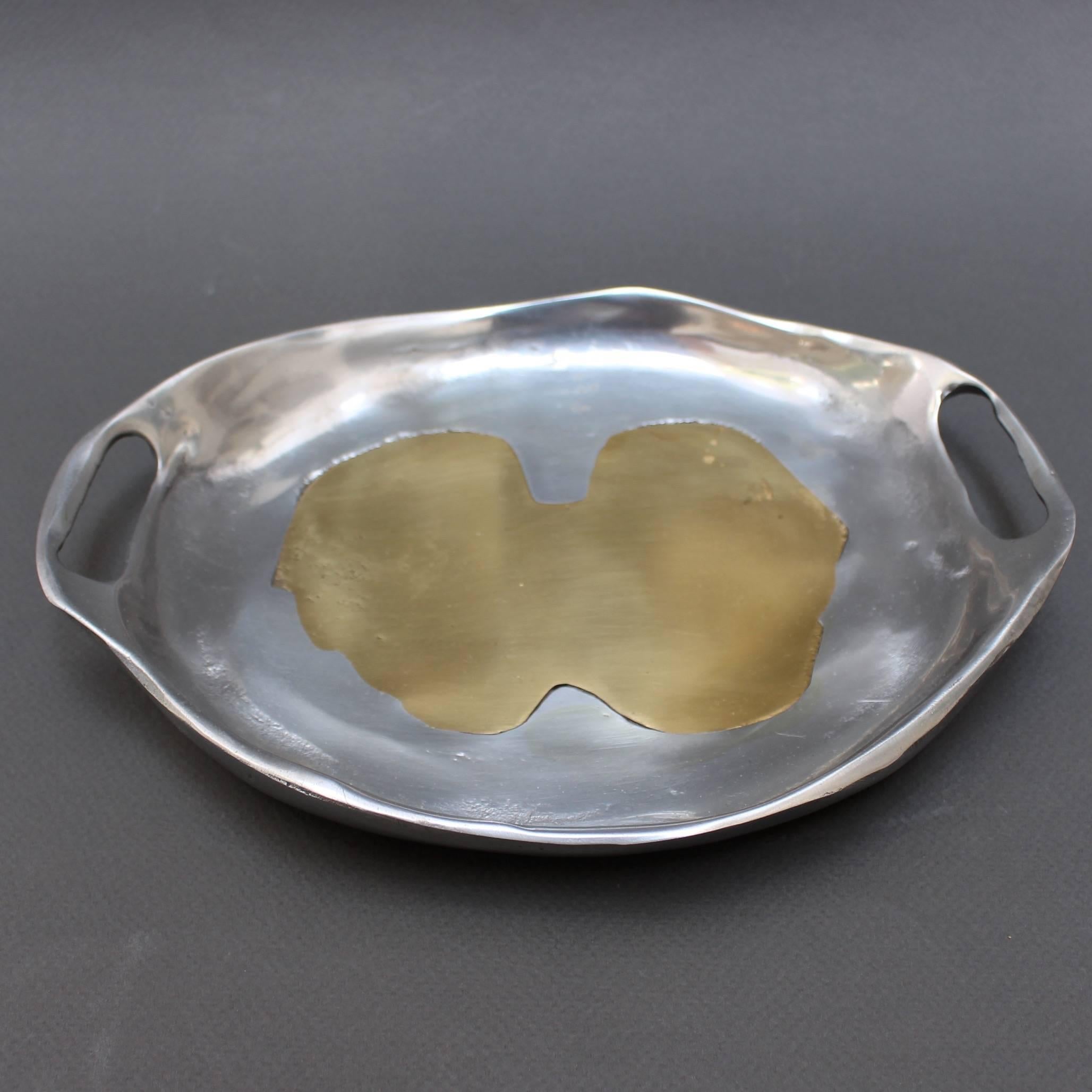 Decorative aluminium and brass tray in the Style of David Marshall. This modernist style tray is perfect for your desk or for home display. Mostly a curvy oval-shaped with abstract brass form in the middle; the tray is very weighty, polished to a