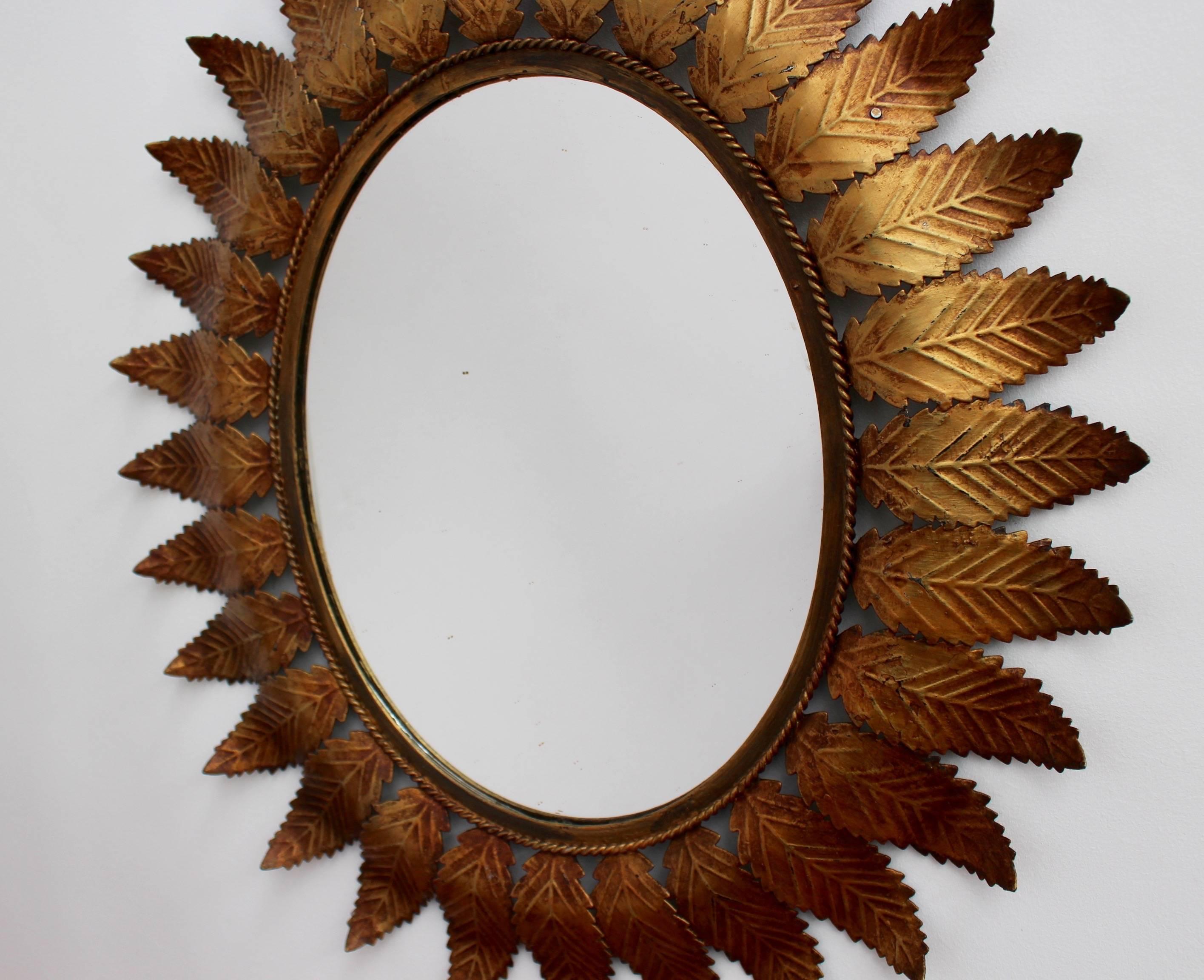 Spanish copper patina sunburst mirror, circa 1950s with leaf motif rays and rope-pattern mirror border. In good vintage condition commensurate with age and use. Some authentic age spots appear on mirror surface adding character while reflecting its
