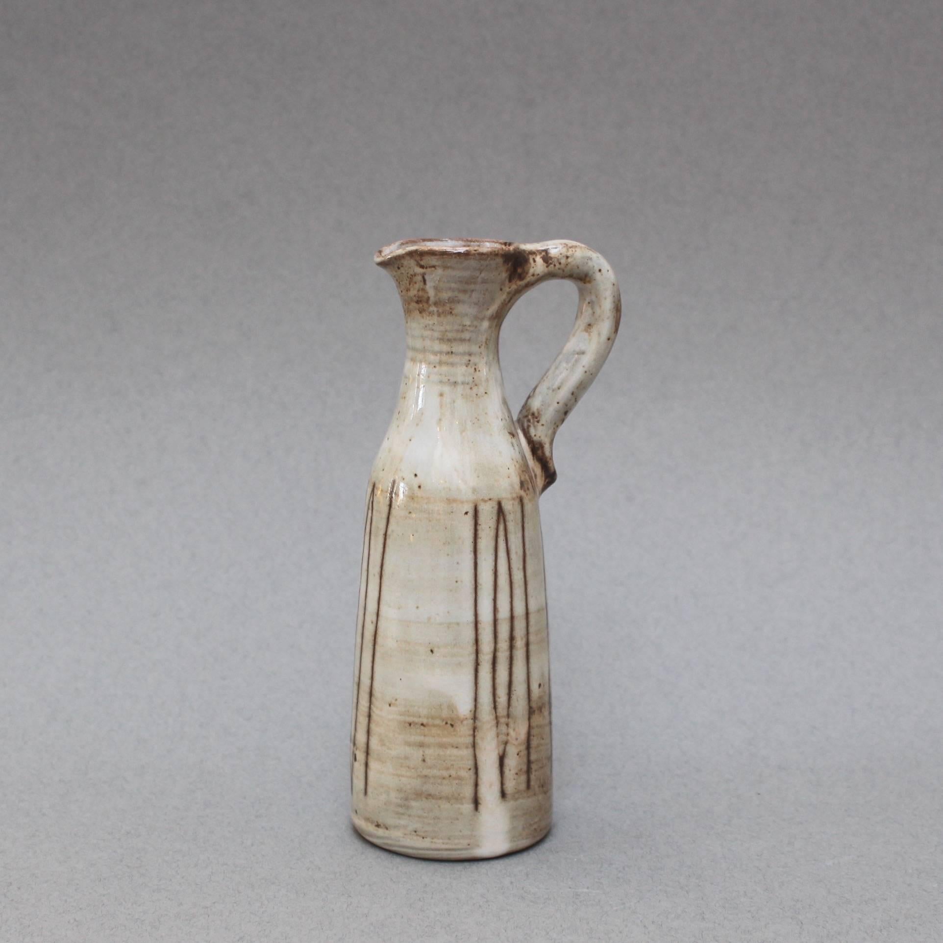 Small ceramic jug with handle by Jacques Pouchain, (circa 1960s). This midcentury ceramic jug is elegantly glazed in light beige with a contemporary brown motif surround. Engraved: 