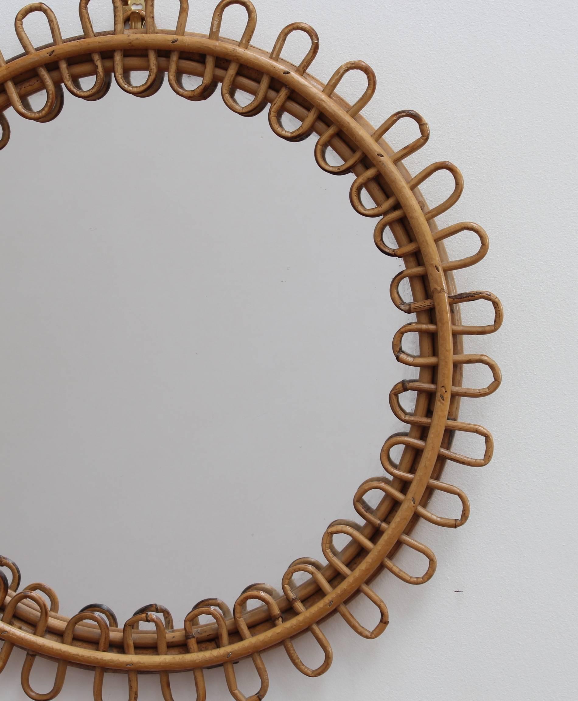 Midcentury Italian rattan and bamboo mirror, (circa 1960s). Chic and stylish circular mirror with bamboo frame and undulating rattan border. Let the sunshine in to your home and your life. In excellent vintage condition commensurate with its age and