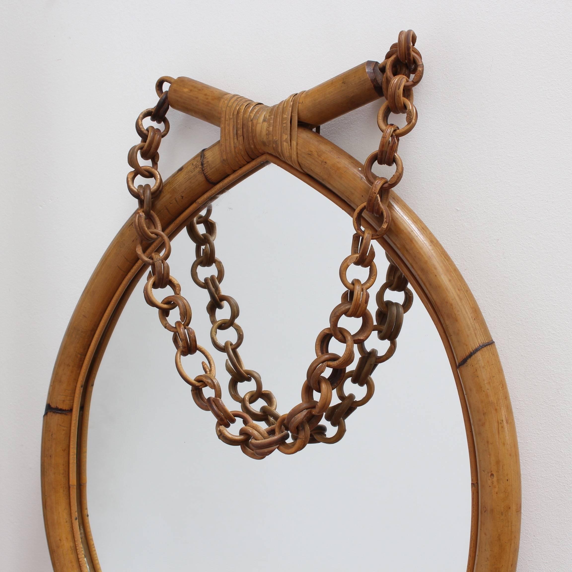 Italian 'eye-shaped' bamboo and rattan wall mirror (circa 1960s). Wide-caned bamboo in the shape of an eye is bound with rattan strips and sports a rattan hanging chain. There is a graceful, aged patina on the mirror frame. In very good vintage